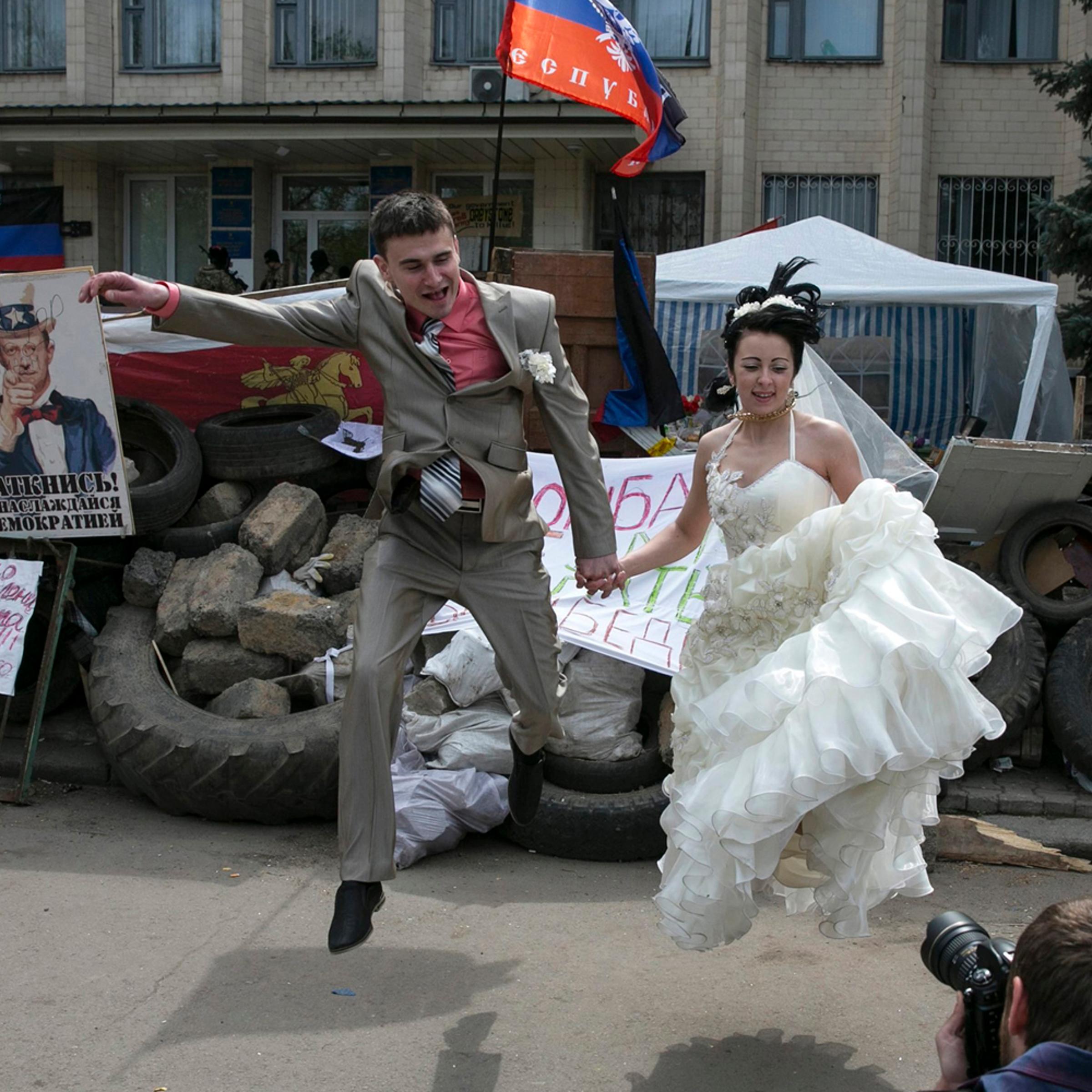 A pair of bride and groom jumps in front of barricades outside a regional government building seized by pro-Russian armed men in Kramatorsk