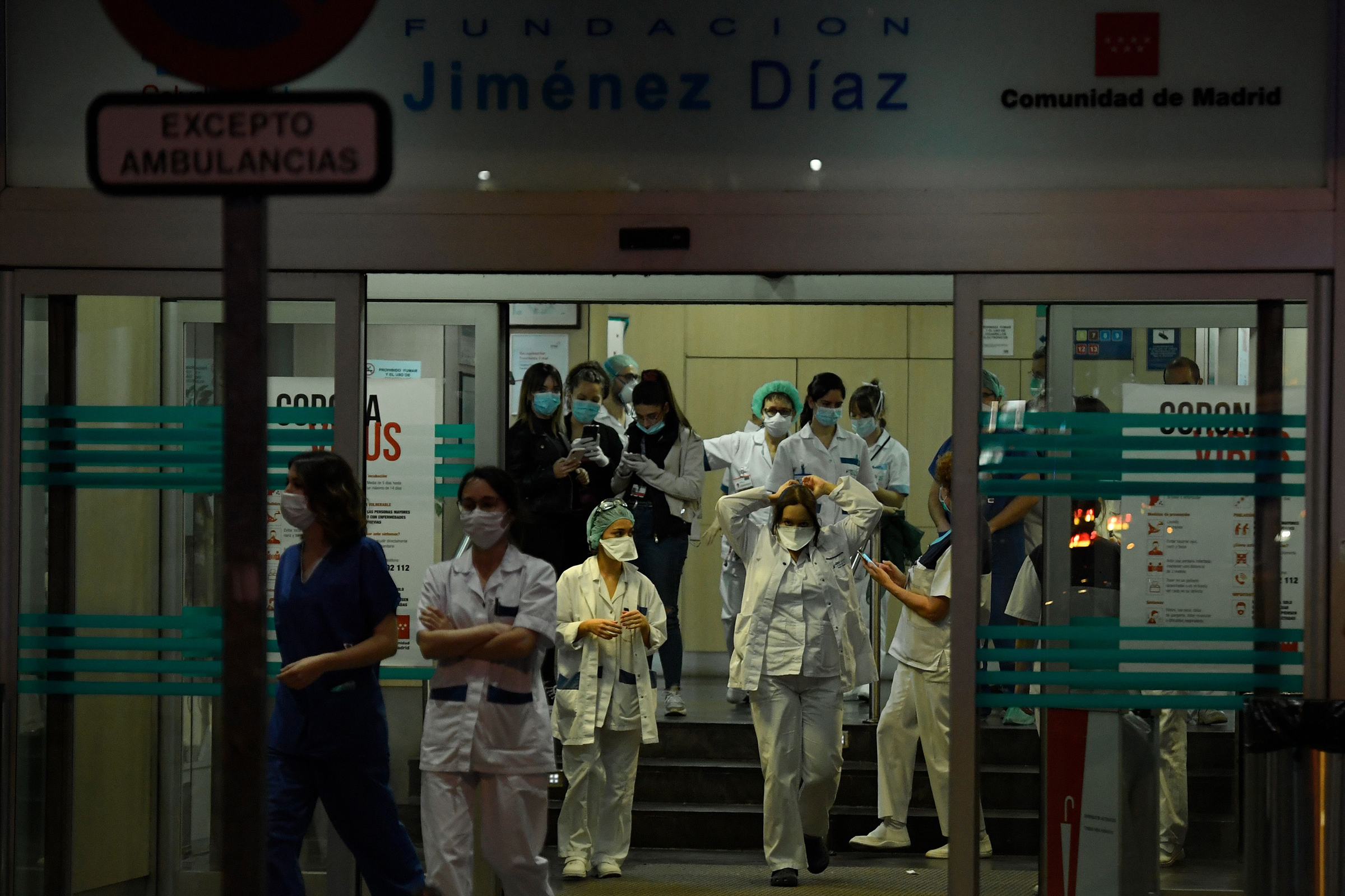 Healthcare workers dealing with the new coronavirus crisis stand at the entrance of the Fundacion Jimenez Diaz hospital in Madrid on March 25