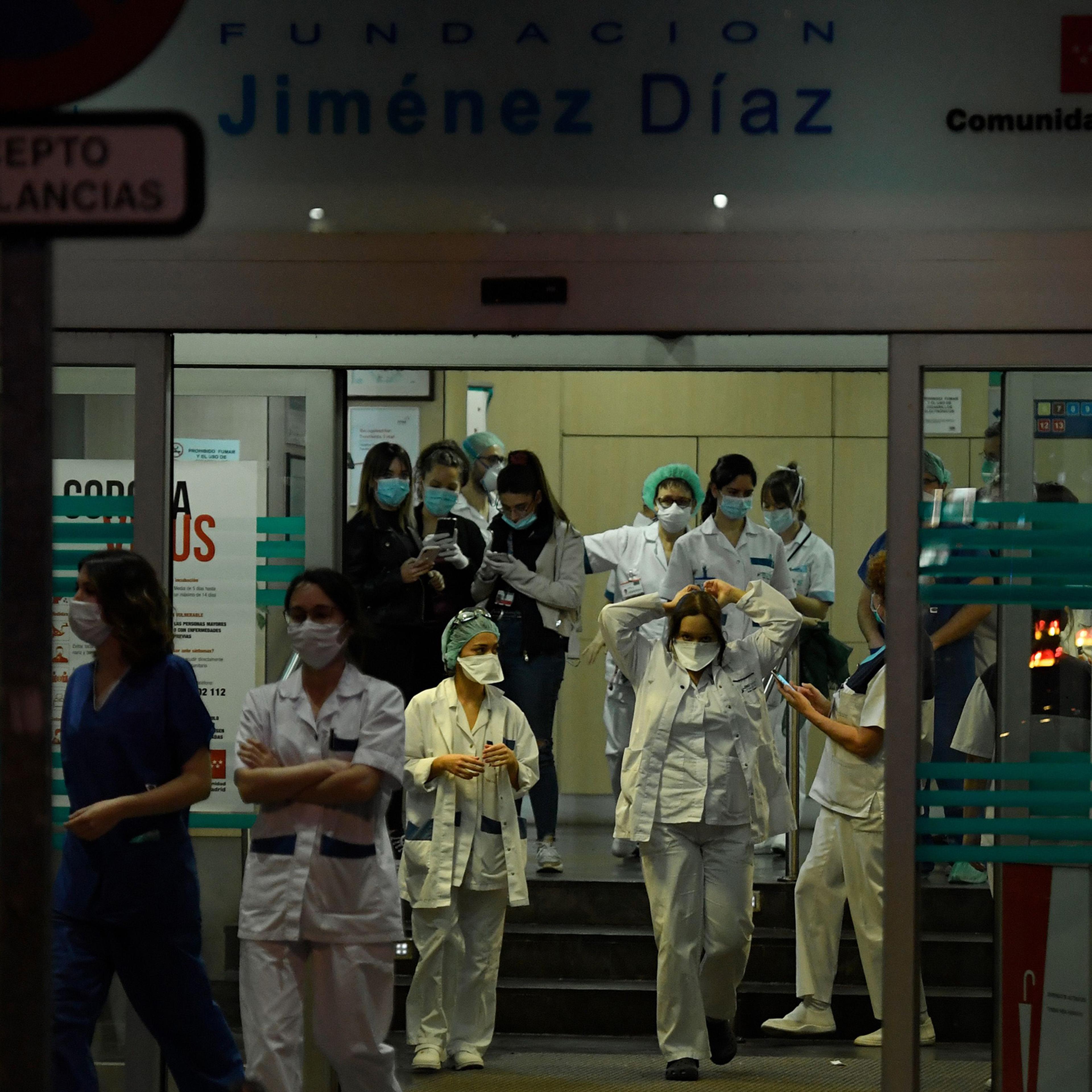 Healthcare workers dealing with the new coronavirus crisis stand at the entrance of the Fundacion Jimenez Diaz hospital in Madrid on March 25