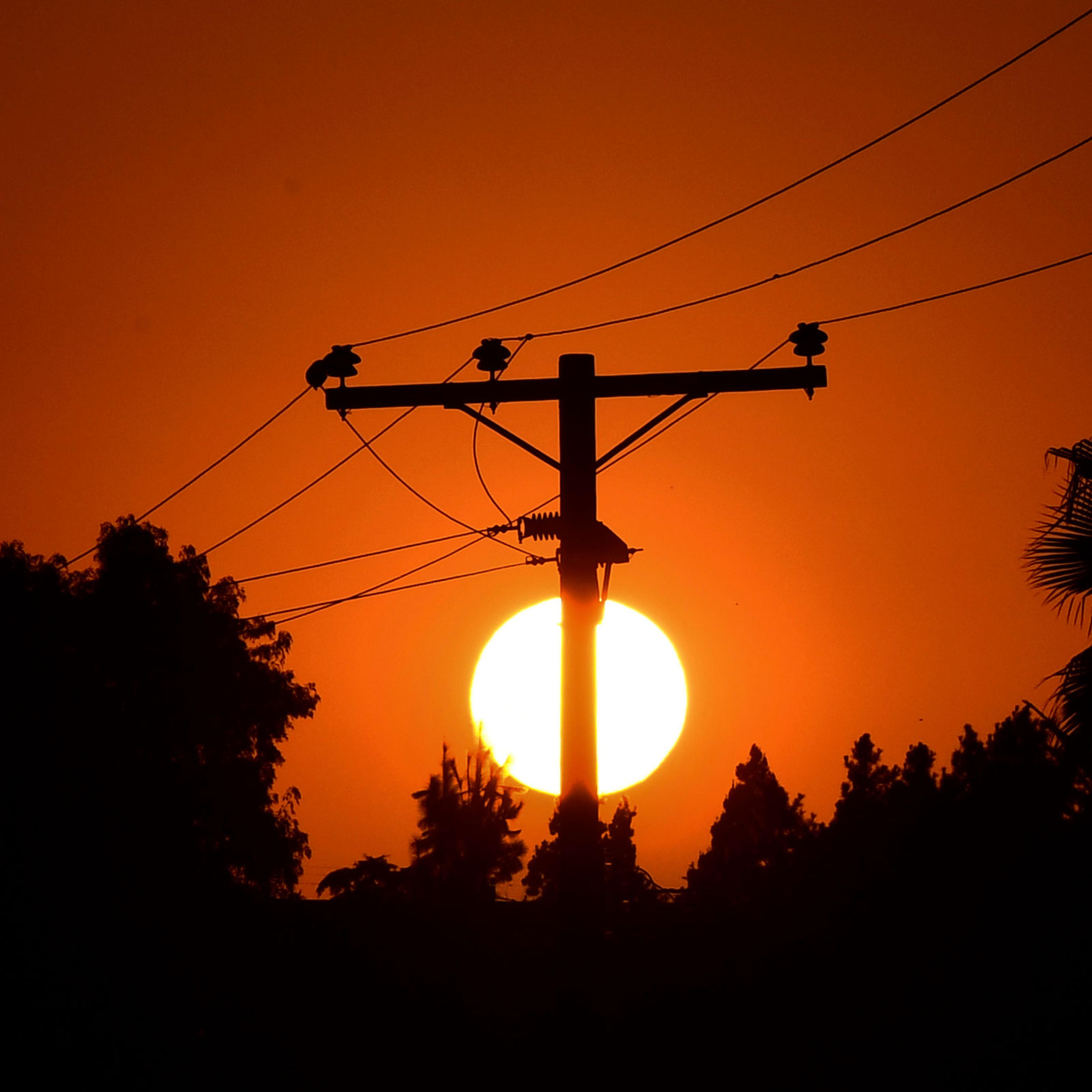 The sun sets behind power lines in Los Angeles