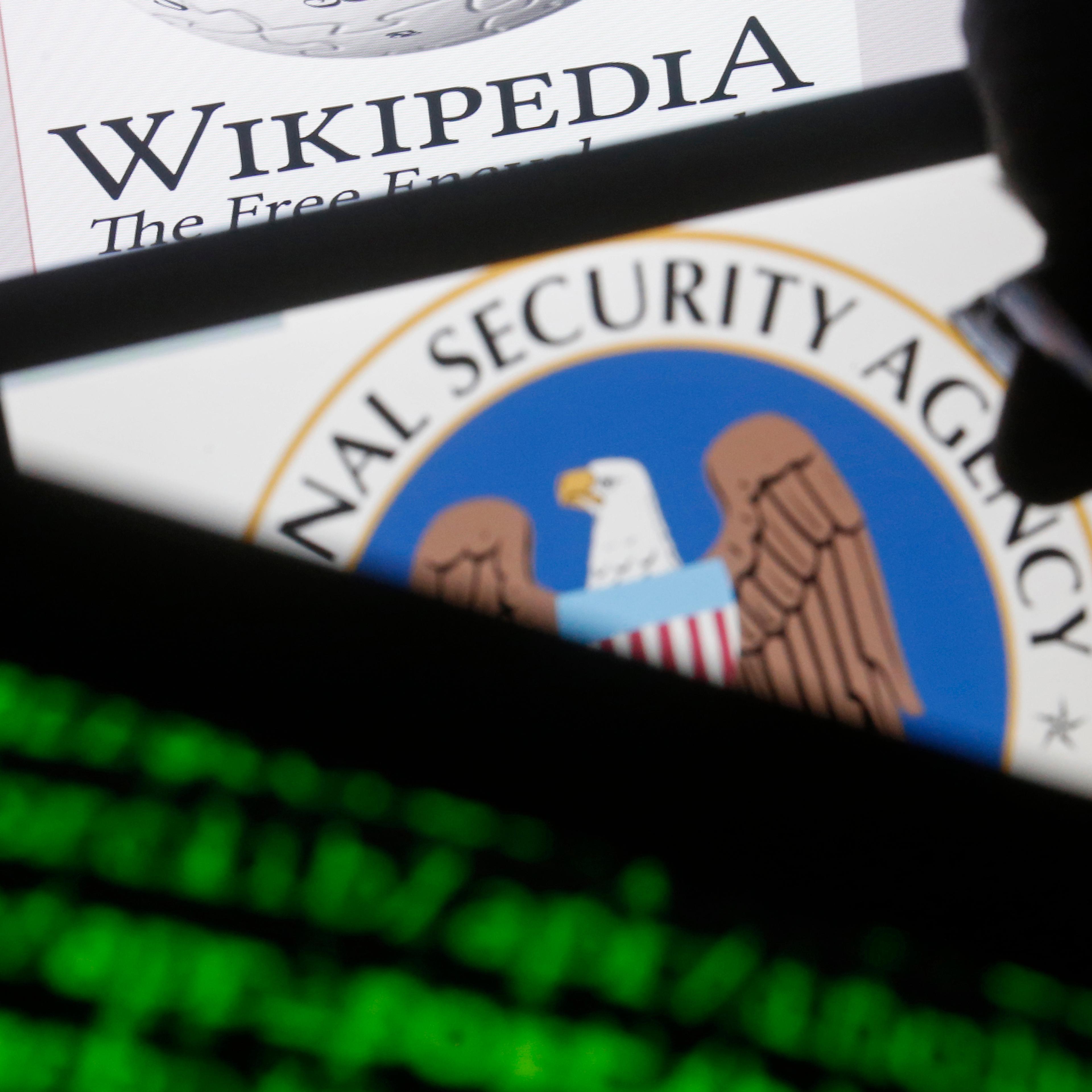 A man is seen near cyber code and the U.S. National Security Agency logo in this photo illustration taken in Sarajevo