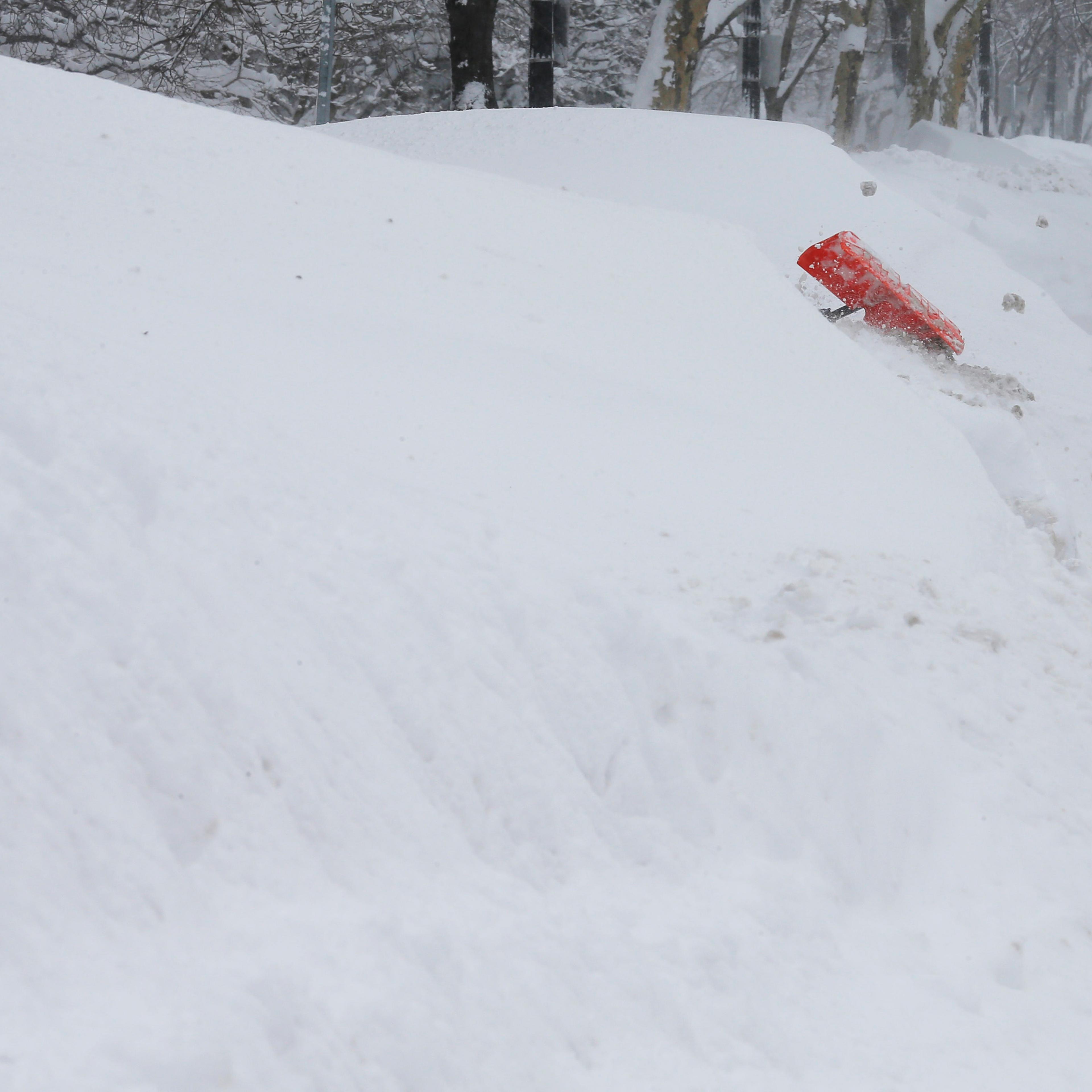 Worker digs a path through the large snow mounds on Beacon Street during a winter blizzard in Boston