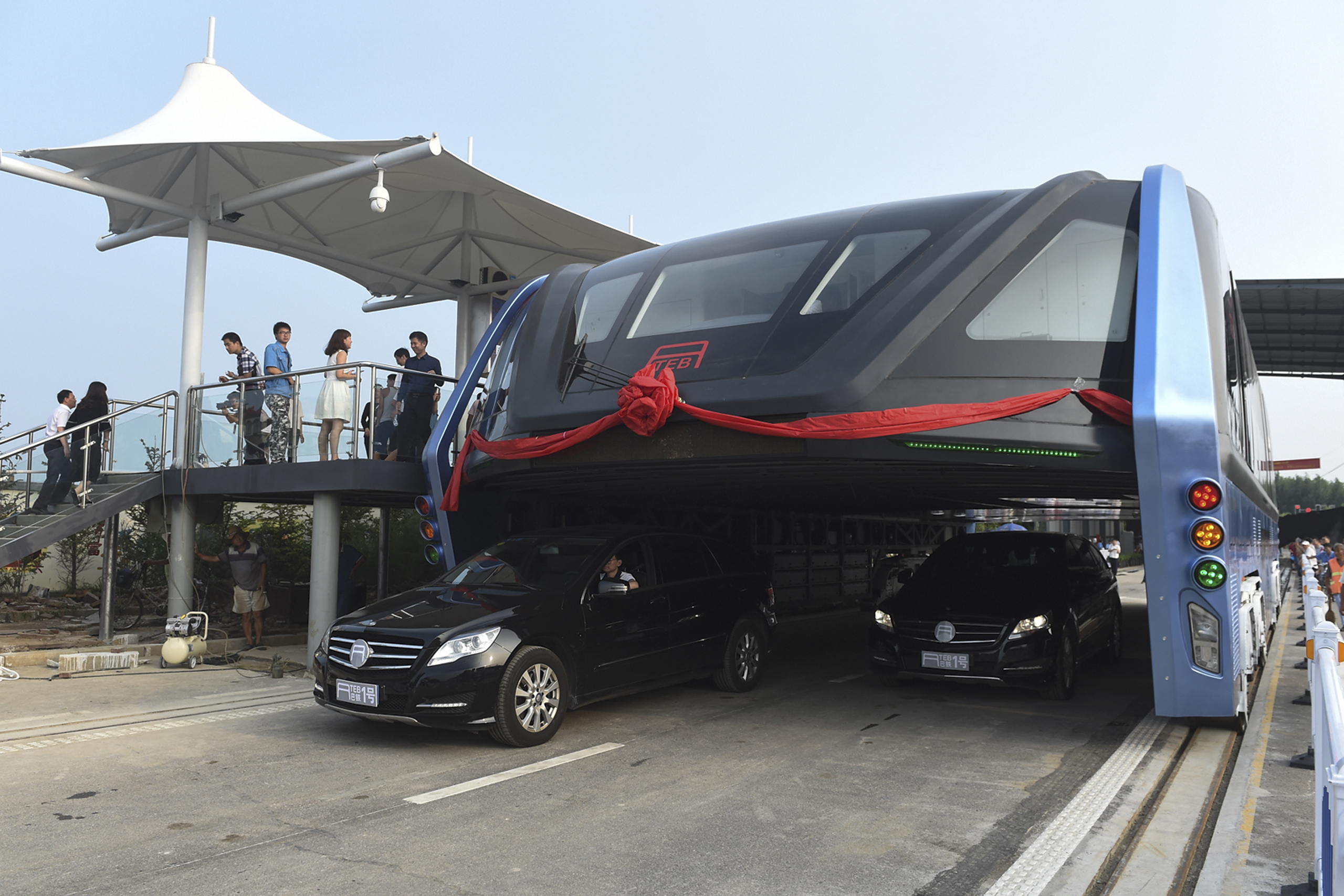 People stand on a platform as the Transit Elevated Bus TEB-1 conducting a test run after it unveiled in Qinhuangdao, north China's Hebei Province on Aug. 2, 2016.