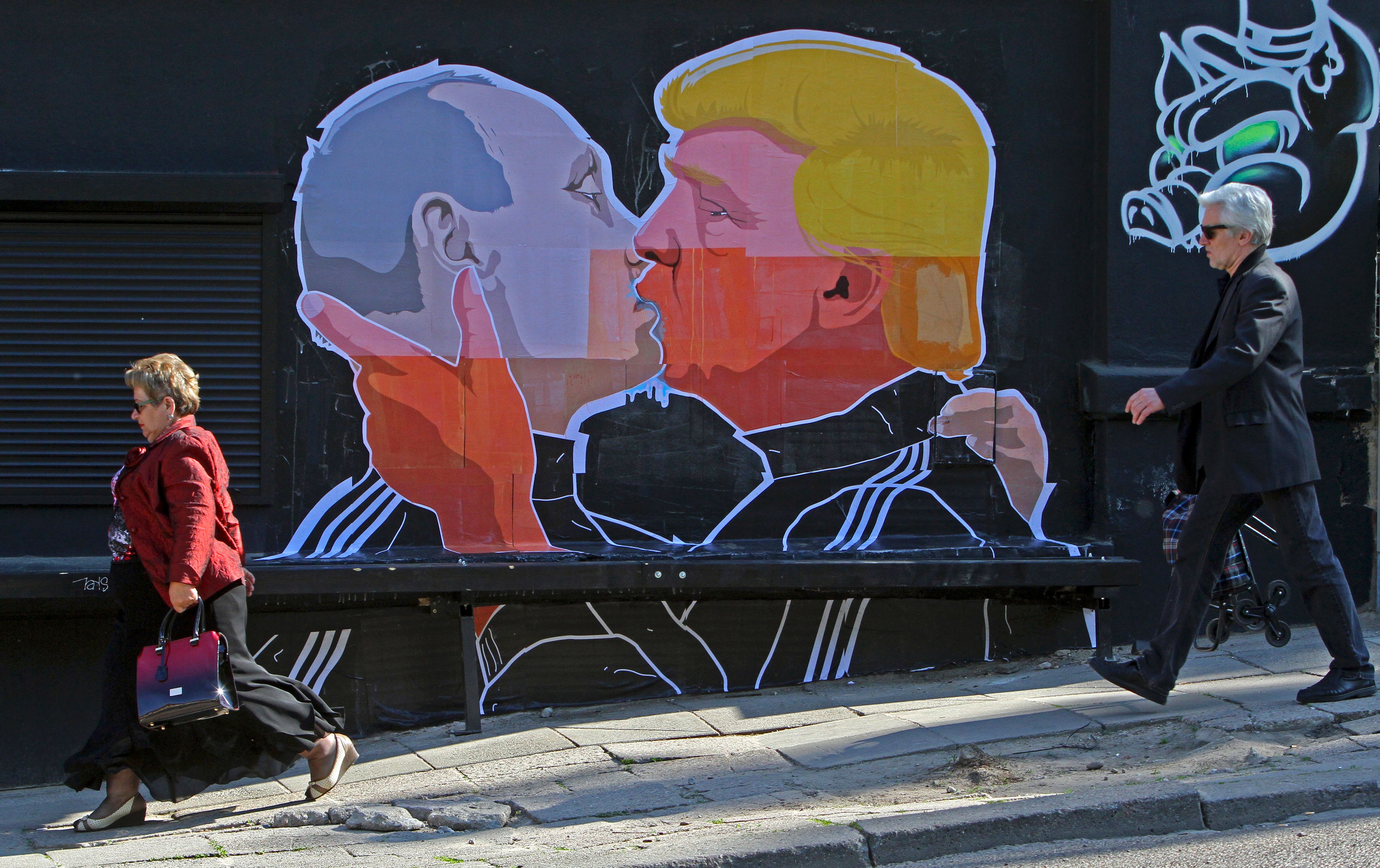 People walk past a mural on a restaurant wall depicting U.S. Presidential hopeful Donald Trump and Russian President Vladimir Putin greeting each other with a kiss in the Lithuanian capital Vilnius on May 13, 2016.