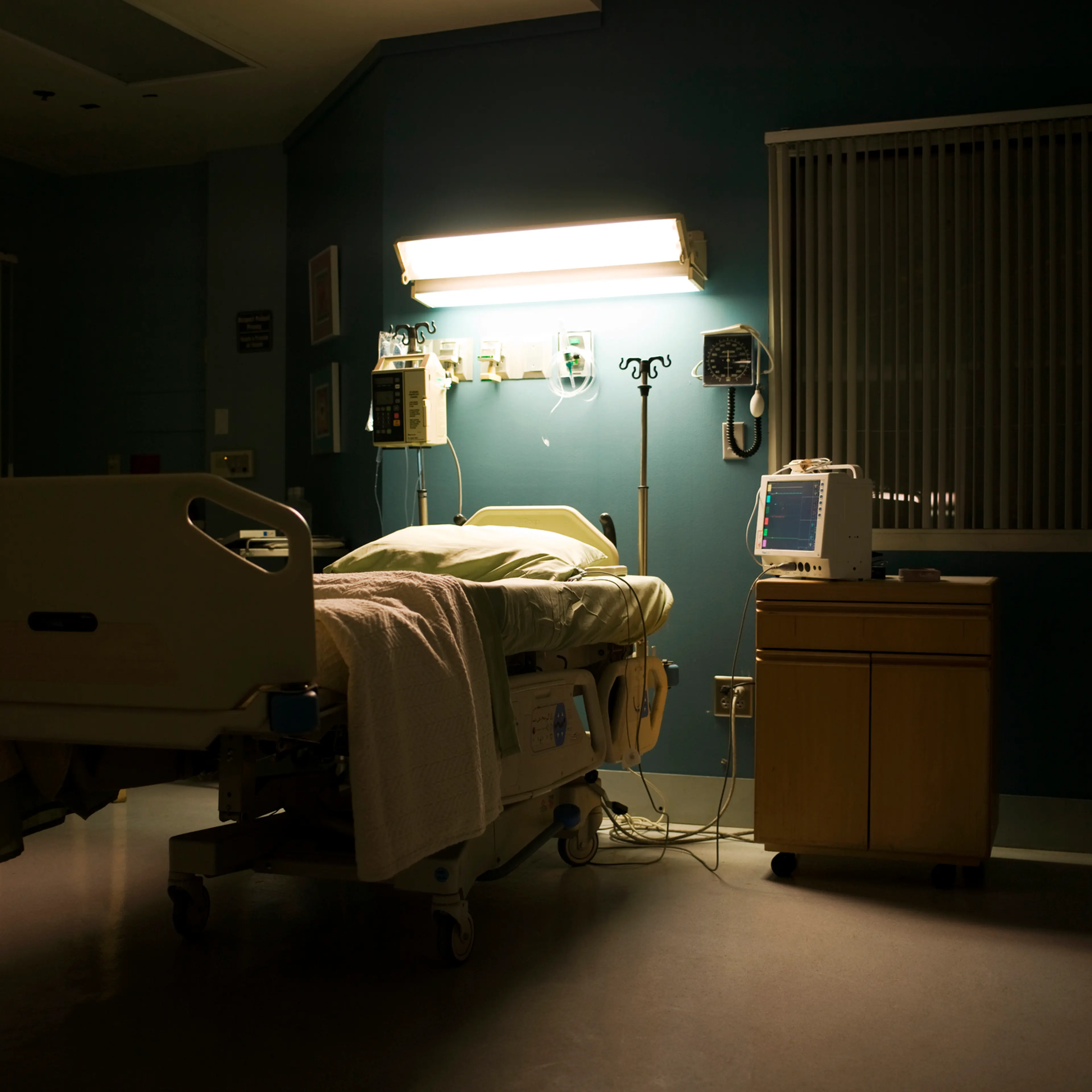 Bed in darkened empty hospital room