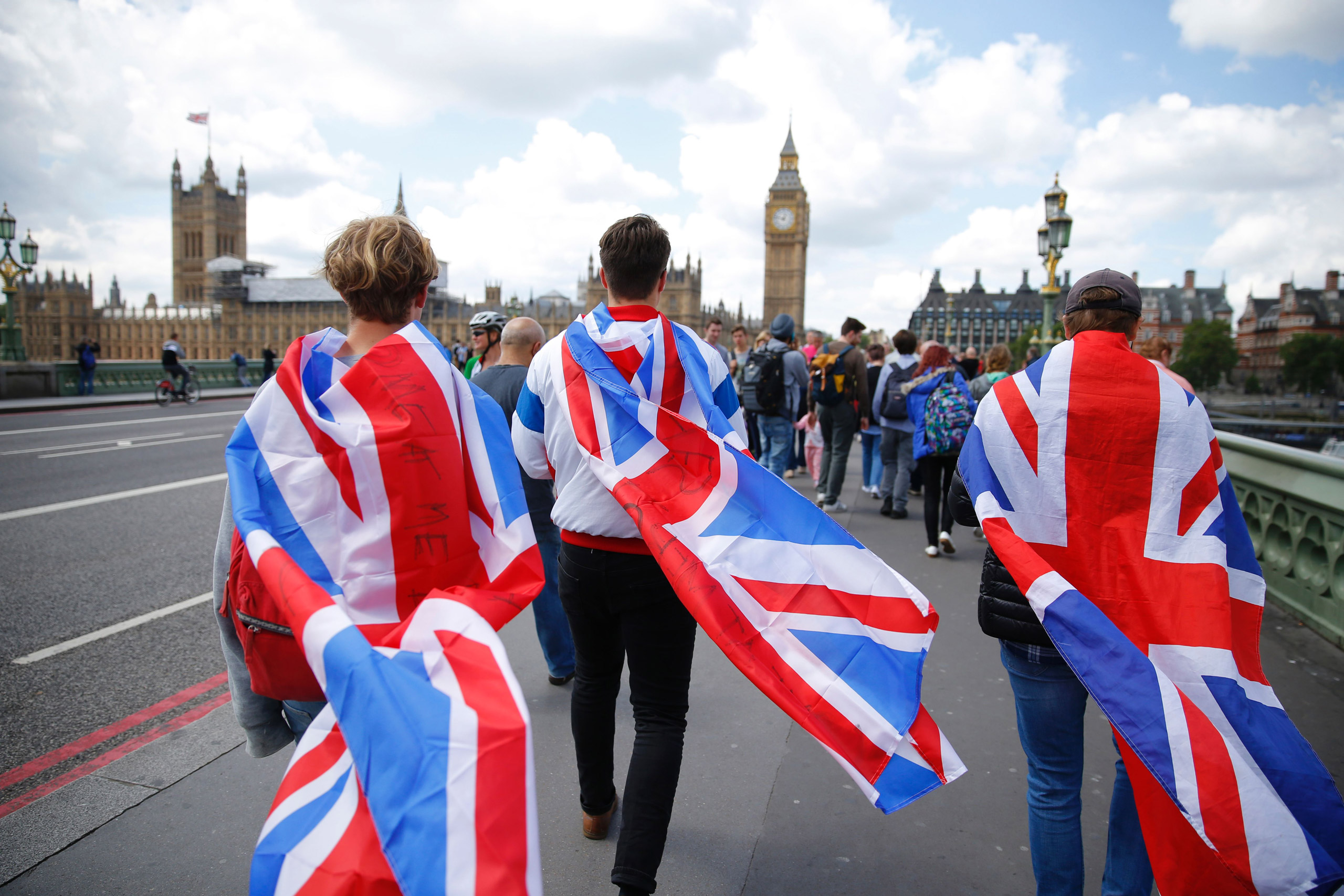 People walk over Westminster Bridge wrapped in Union flags, towards the Queen Elizabeth Tower (Big Ben) and The Houses of Parliament in central London on June 26, 2016. Britain's opposition Labour party plunged into turmoil Sunday and the prospect of Sco