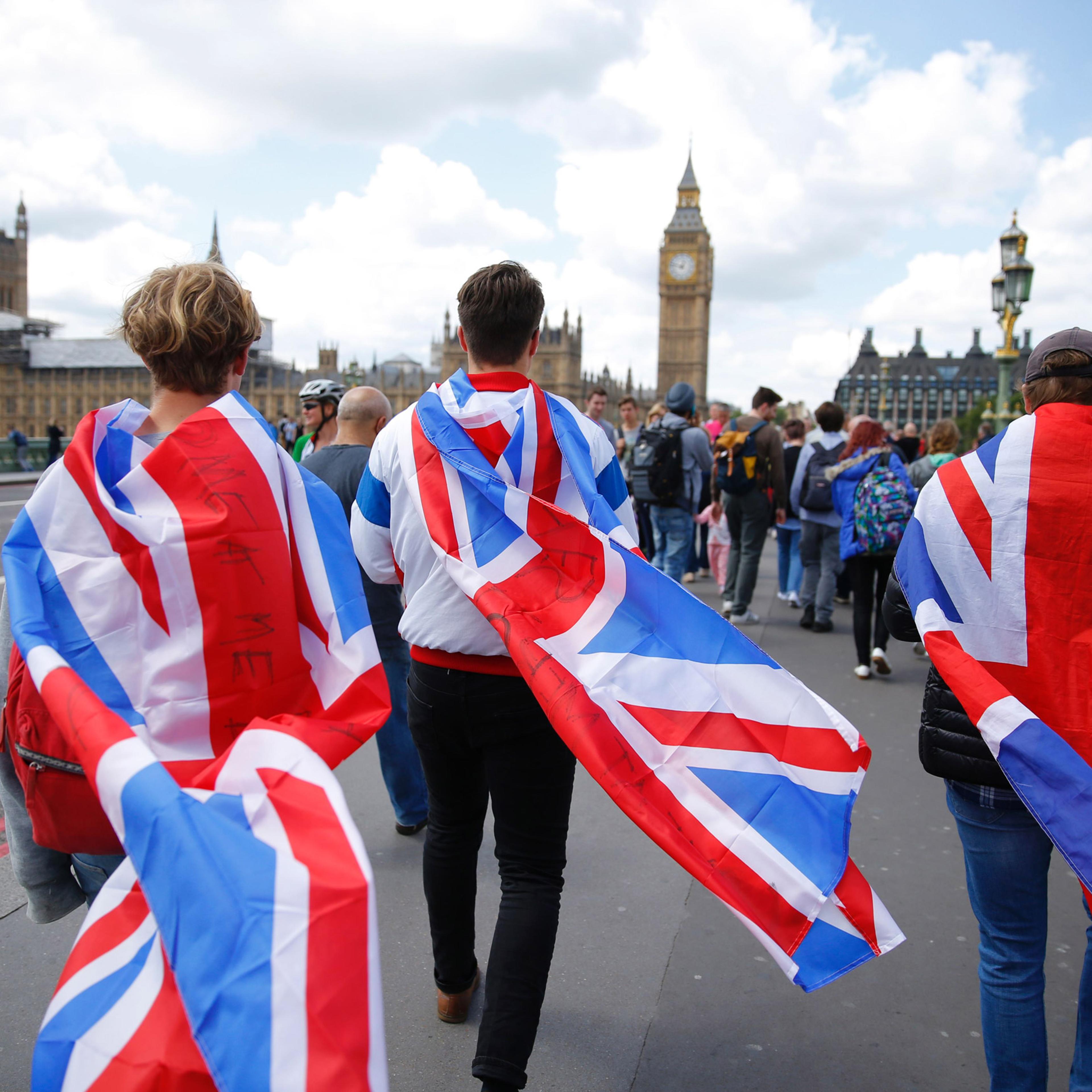 People walk over Westminster Bridge wrapped in Union flags, towards the Queen Elizabeth Tower (Big Ben) and The Houses of Parliament in central London on June 26, 2016. Britain's opposition Labour party plunged into turmoil Sunday and the prospect of Sco