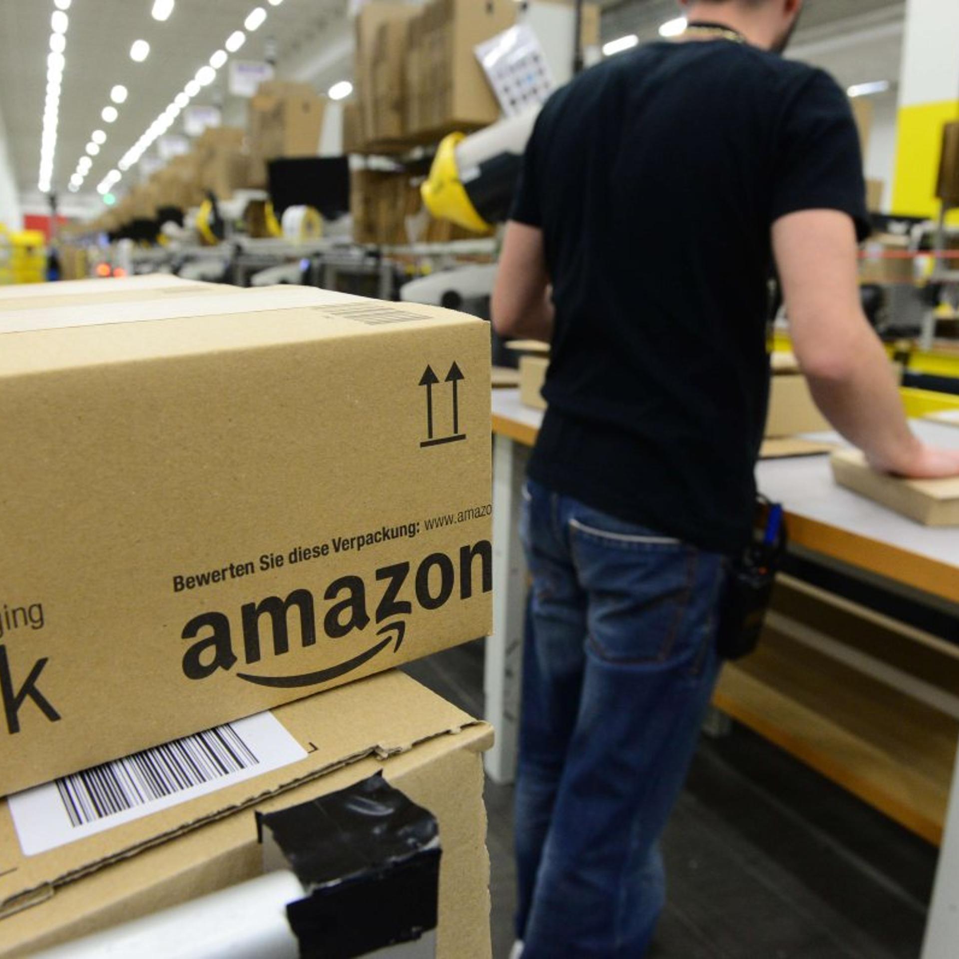 An employee places packed goods on a conveyor belt for shipment at Amazon's Brieselang logistics center west of Berlin on Nov. 11, 2014.