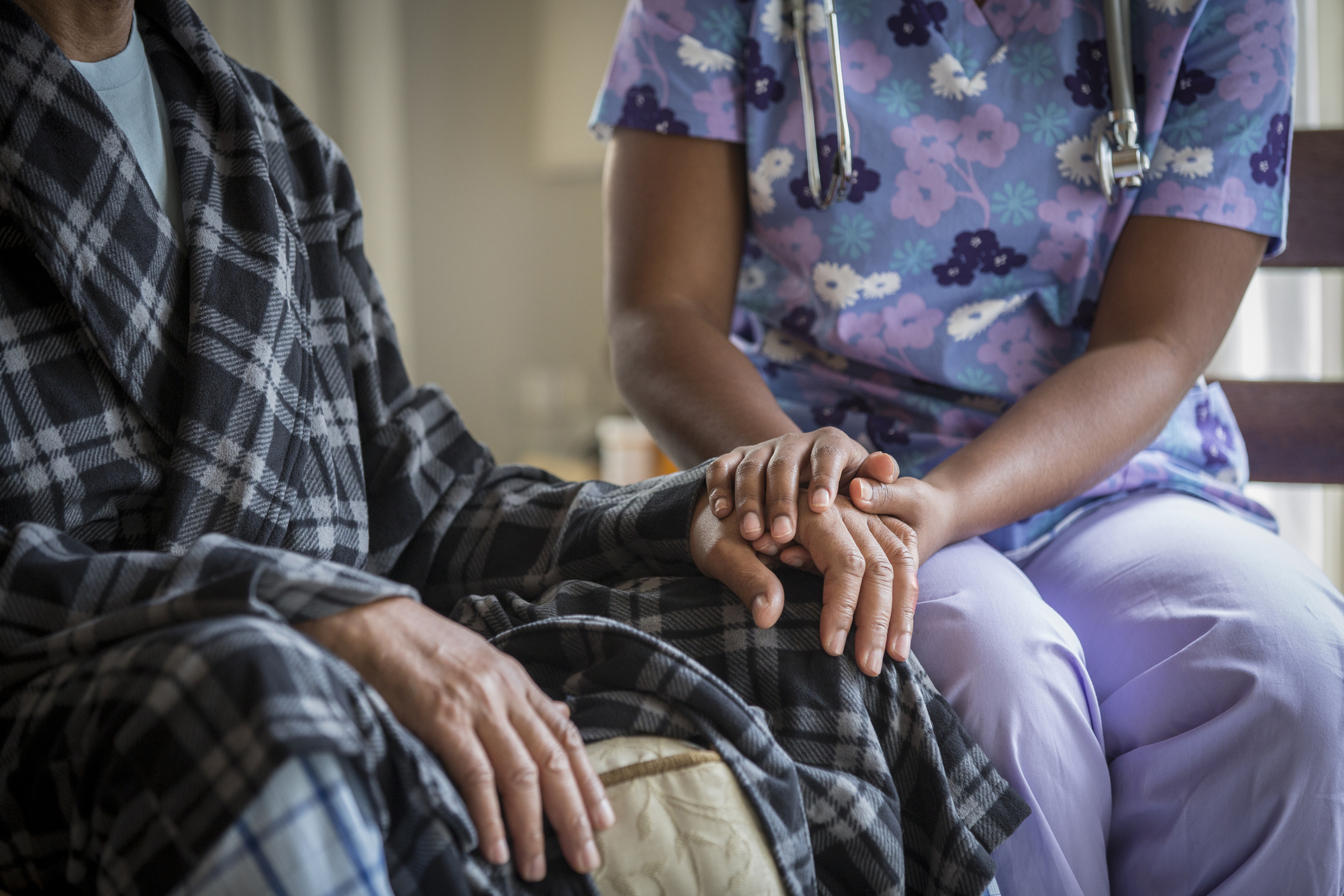 African American nurse holding patient's hand