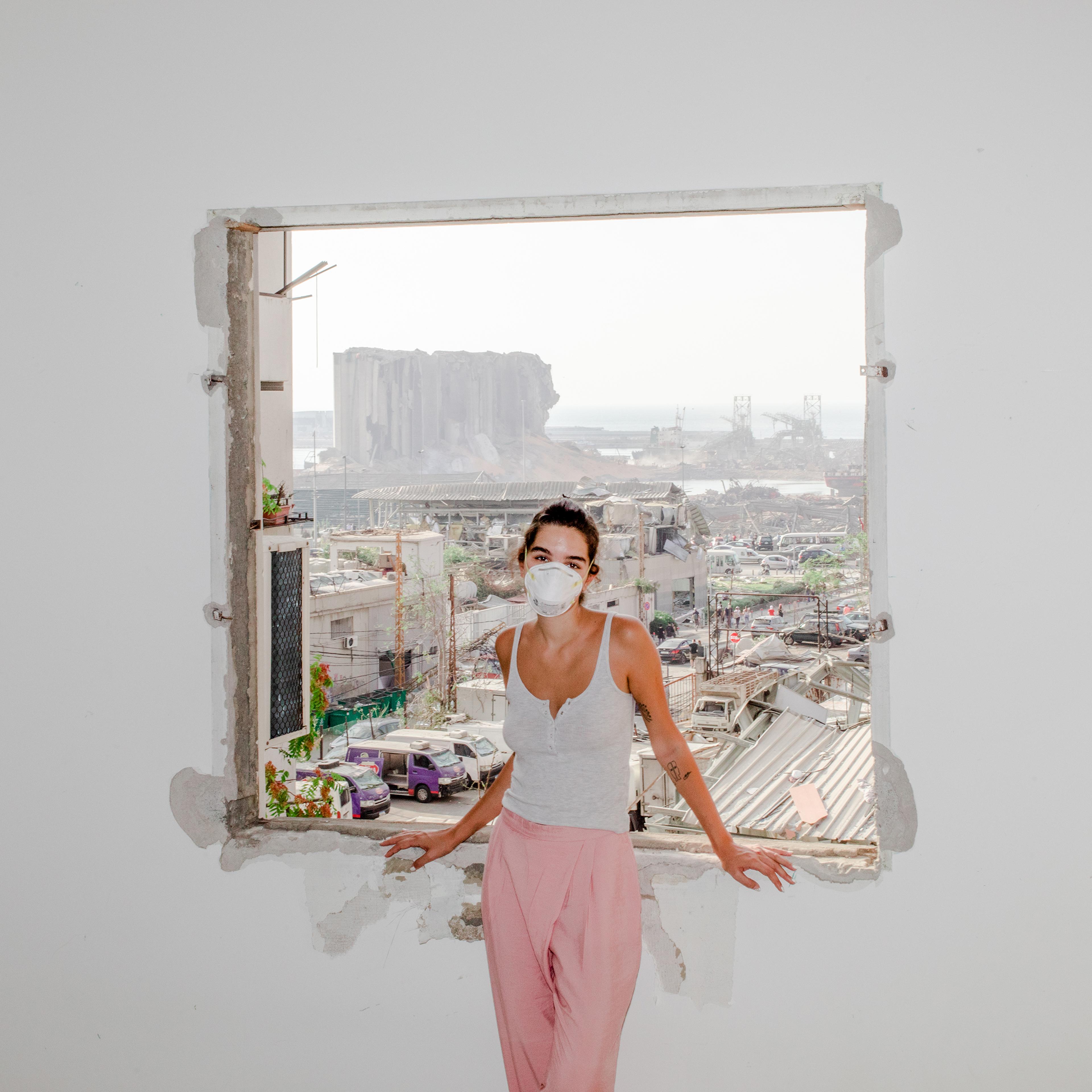 Nour Saliba stands in her apartment in the Mar Mikhael area of Beirut on Aug. 6, two days after the deadly explosion at the city’s port, seen through her blown-out window. “Honestly, I had it easy. I only lost my home. I am one of the lucky ones who stil