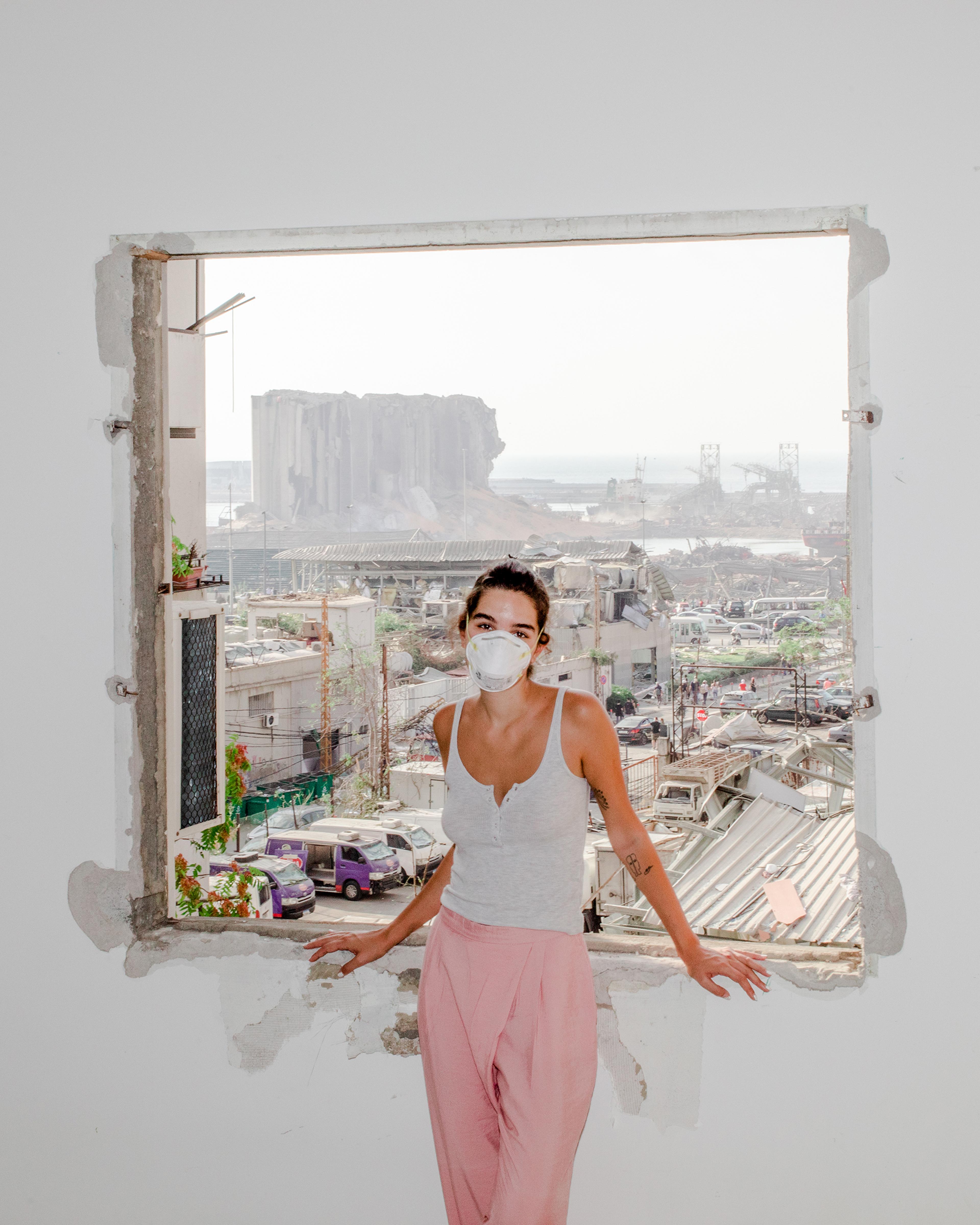 Nour Saliba stands in her apartment in the Mar Mikhael area of Beirut on Aug. 6, two days after the deadly explosion at the city’s port, seen through her blown-out window. “Honestly, I had it easy. I only lost my home. I am one of the lucky ones who stil
