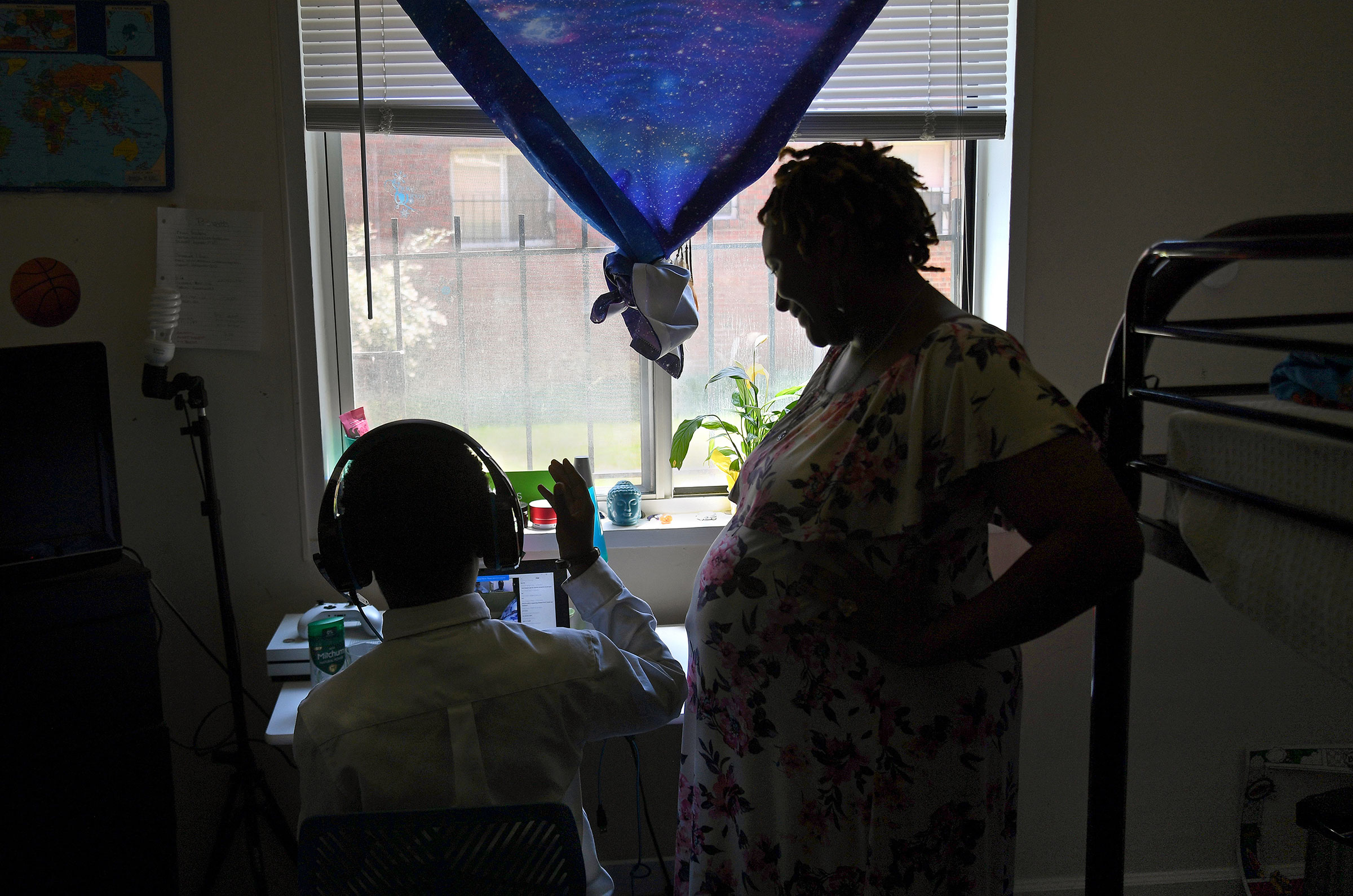 Lakeisha Rollins checks in on her son Amari, age 8, as he does remote summer school work in her apartment in Washington, D.C. on July 14, 2020. Rollins is a single mother who is pregnant with her second child and when the pandemic hit in March, she bunke