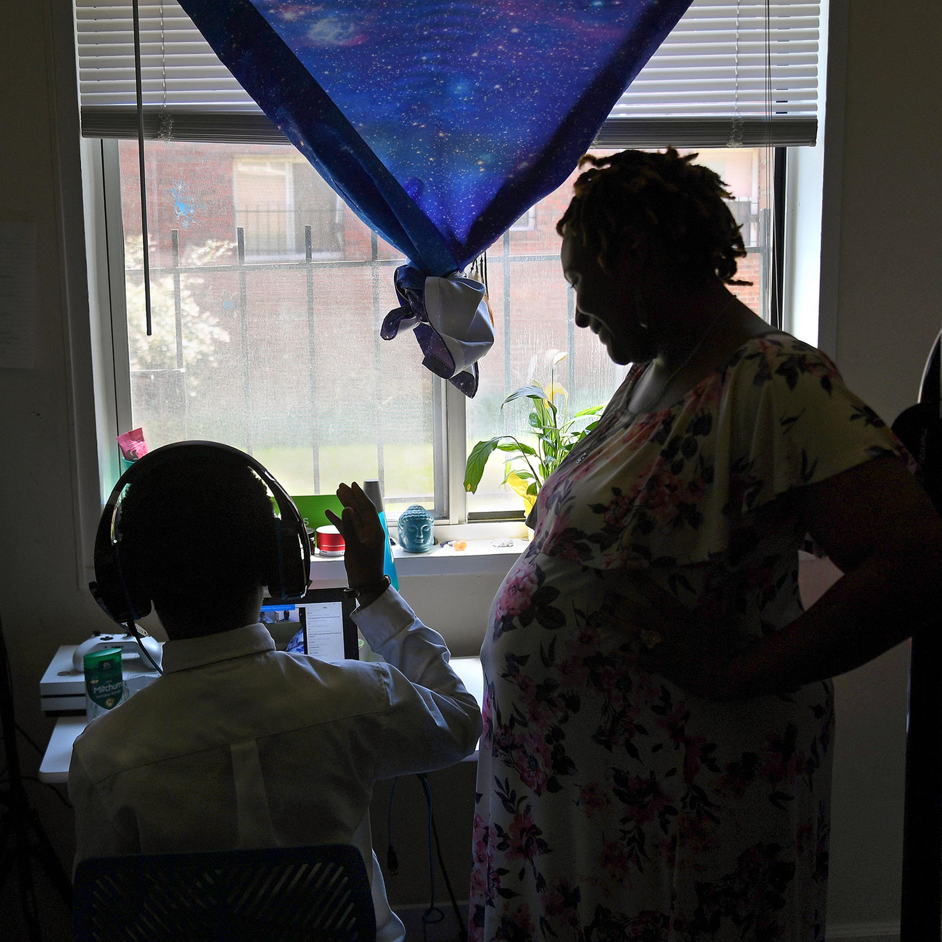 Lakeisha Rollins checks in on her son Amari, age 8, as he does remote summer school work in her apartment in Washington, D.C. on July 14, 2020. Rollins is a single mother who is pregnant with her second child and when the pandemic hit in March, she bunke