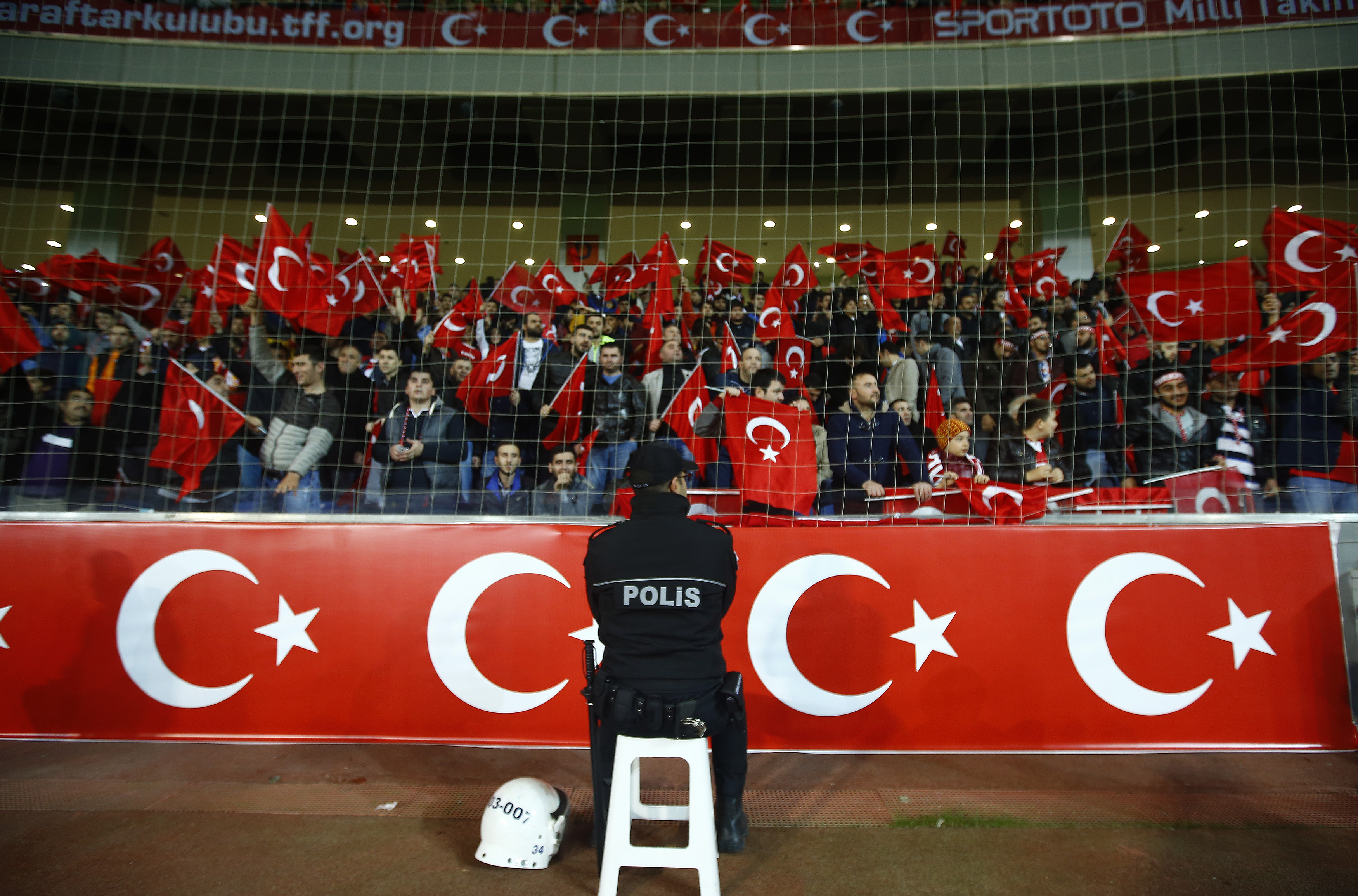 Policeman stands guard in front of supporters of Turkey during their international friendly soccer match against Greece at Basaksehir Fatih Terim stadium in Istanbul