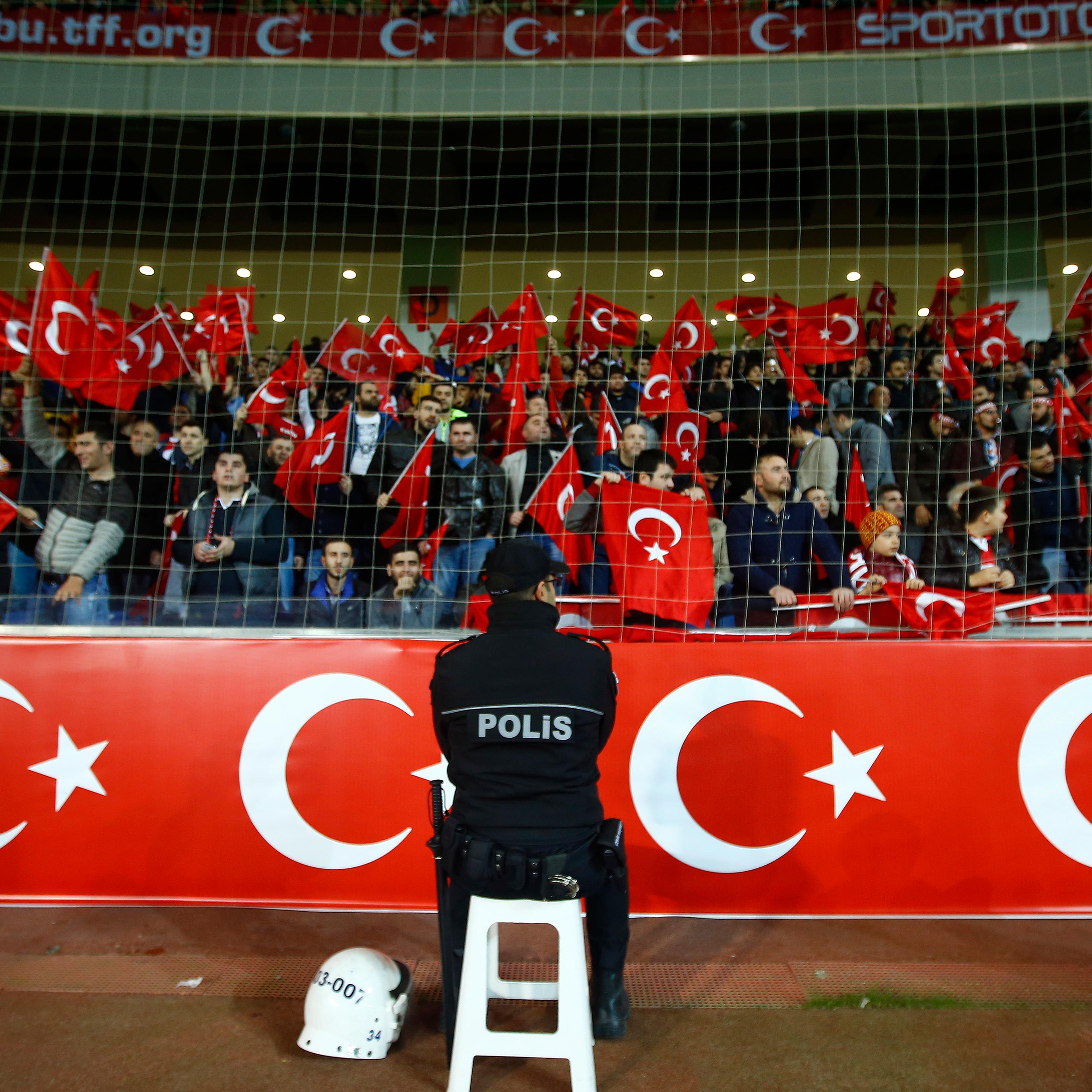 Policeman stands guard in front of supporters of Turkey during their international friendly soccer match against Greece at Basaksehir Fatih Terim stadium in Istanbul