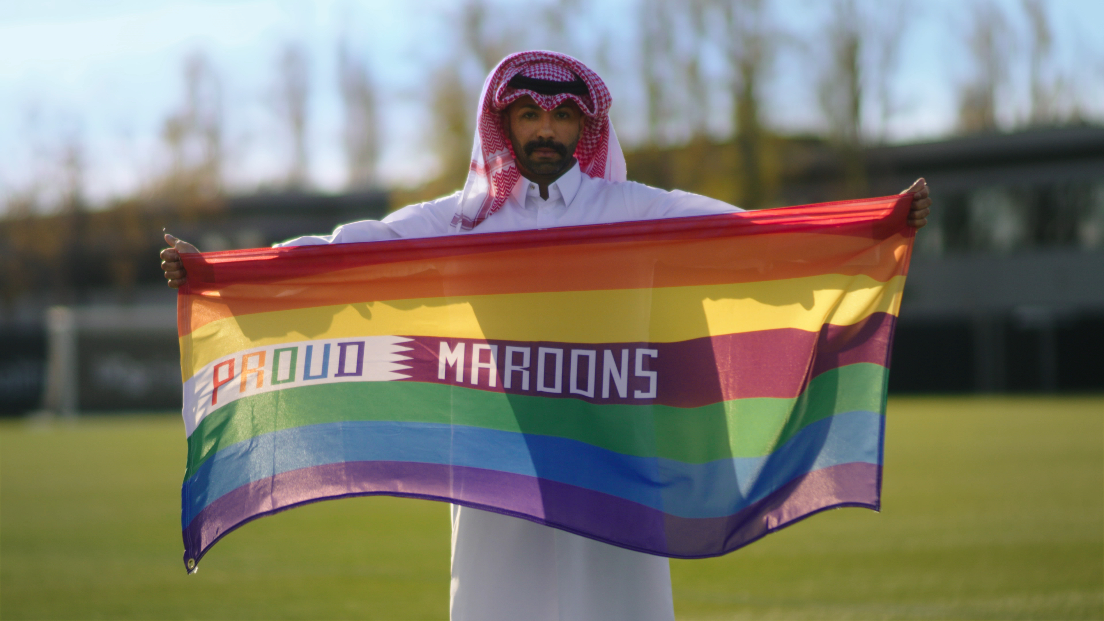 Dr. Naser Mohamed holds a "Proud Maroons" rainbow flag. 