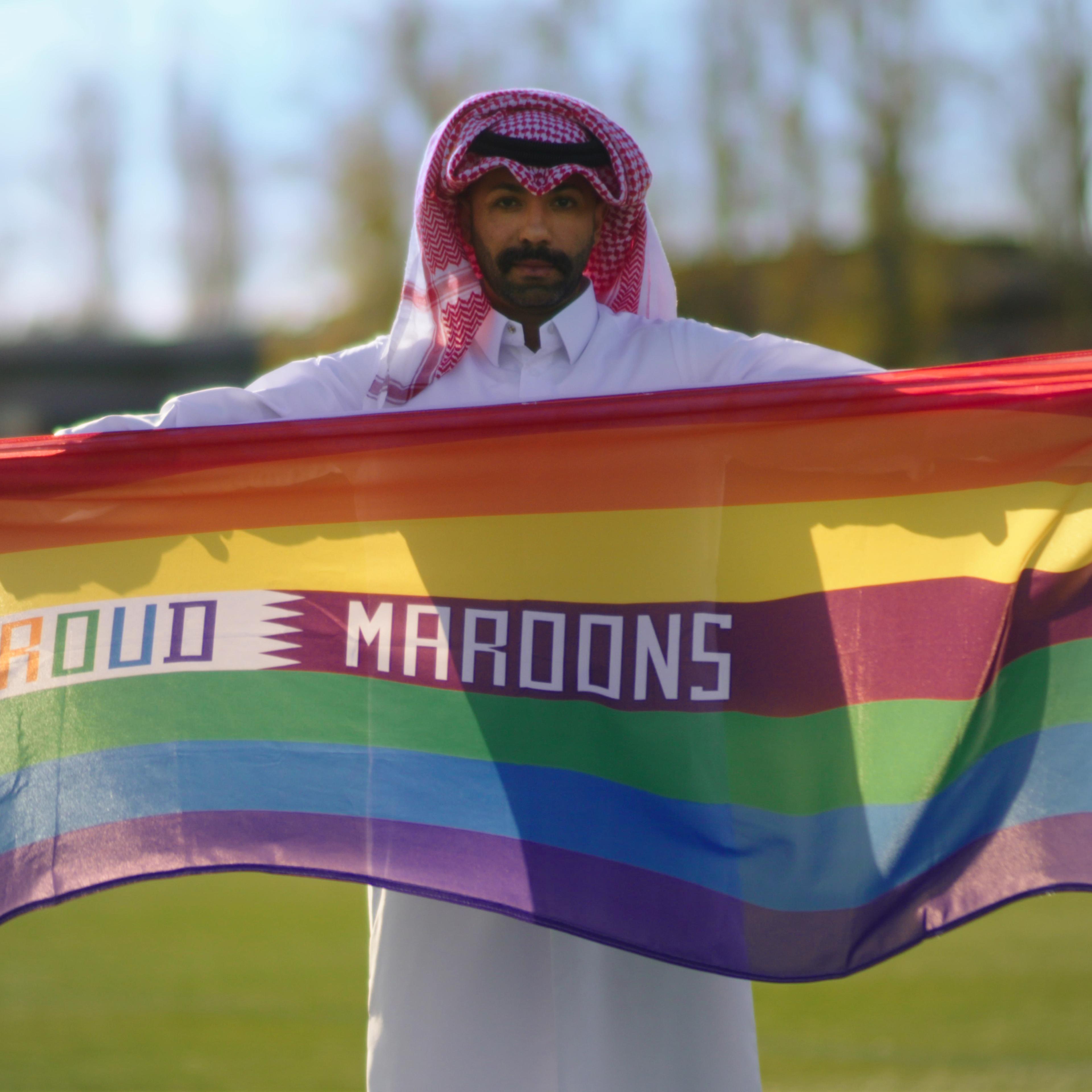 Dr. Naser Mohamed holds a "Proud Maroons" rainbow flag.