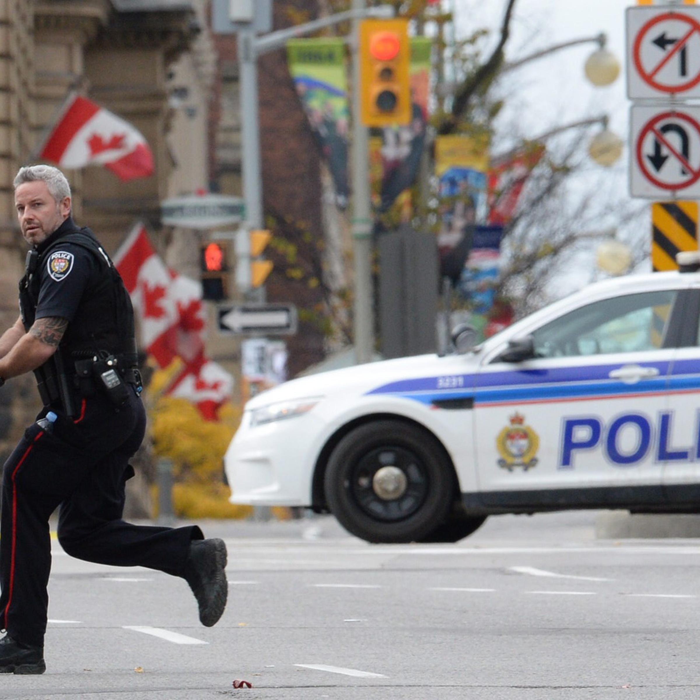 An Ottawa police officer runs with his weapon drawn outside Parliament Hill in Ottawa on Oct. 22, 2014.