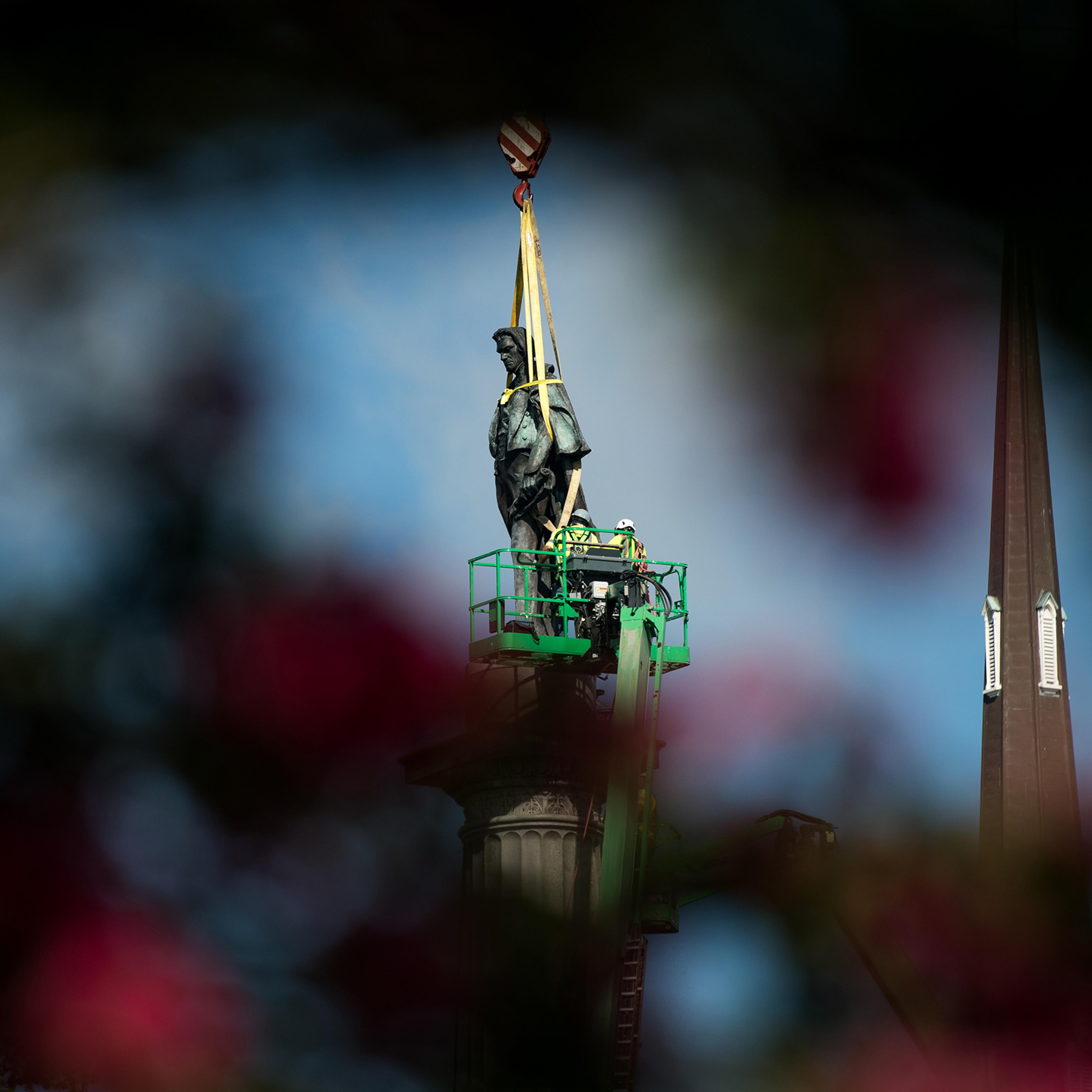 Workers dismantle the John C. Calhoun statue atop a monument in Marion Square in Charleston, S.C., on June 24, 2020.