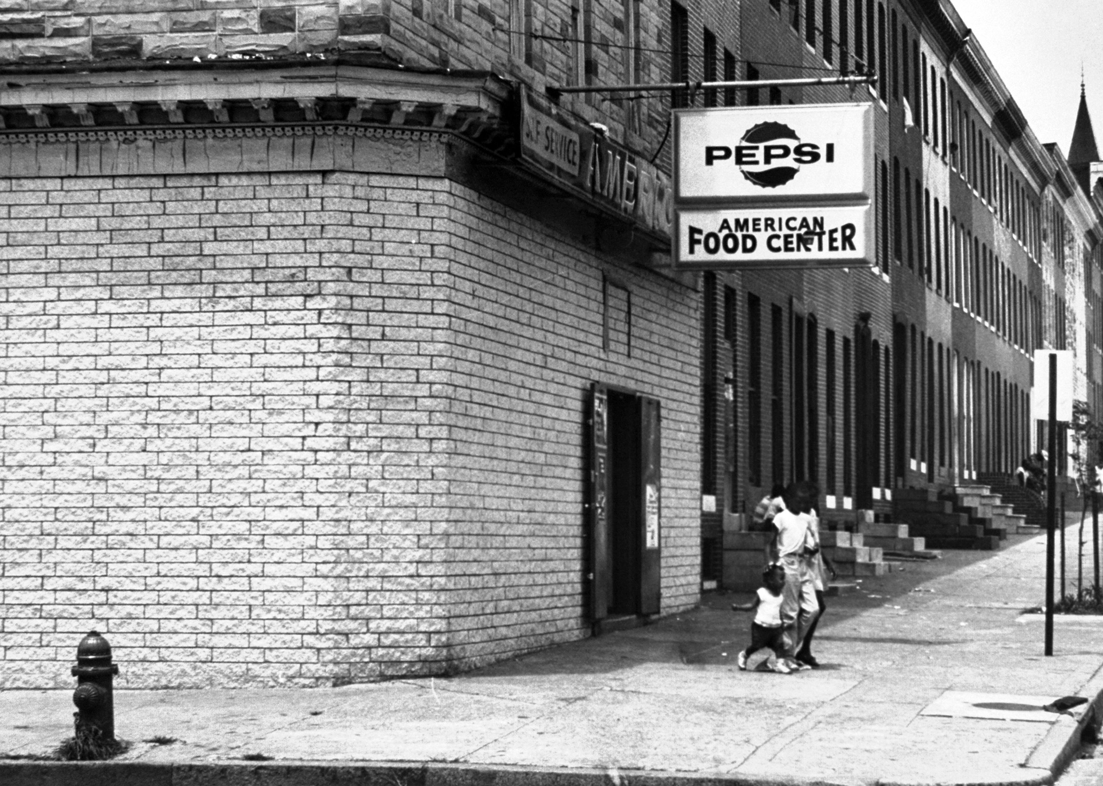 At a grocery, faint outlines around the new brick betray the former presence of shop windows.