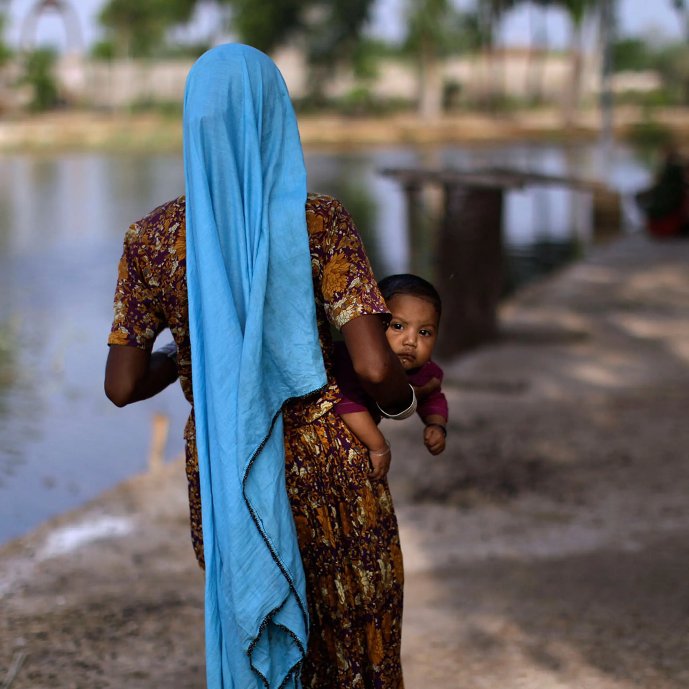 September 22, 2011. A displaced Pakistani child looks on while being held by her mother as they and others take refuge in a college in Tando Muhammad Khan near Hyderabad, Pakistan, after fleeing their flood-hit homes. Many people are still stranded by floods that first hit Pakistan in August following unusually heavy monsoon rains and have affected at least 5.4 million people.