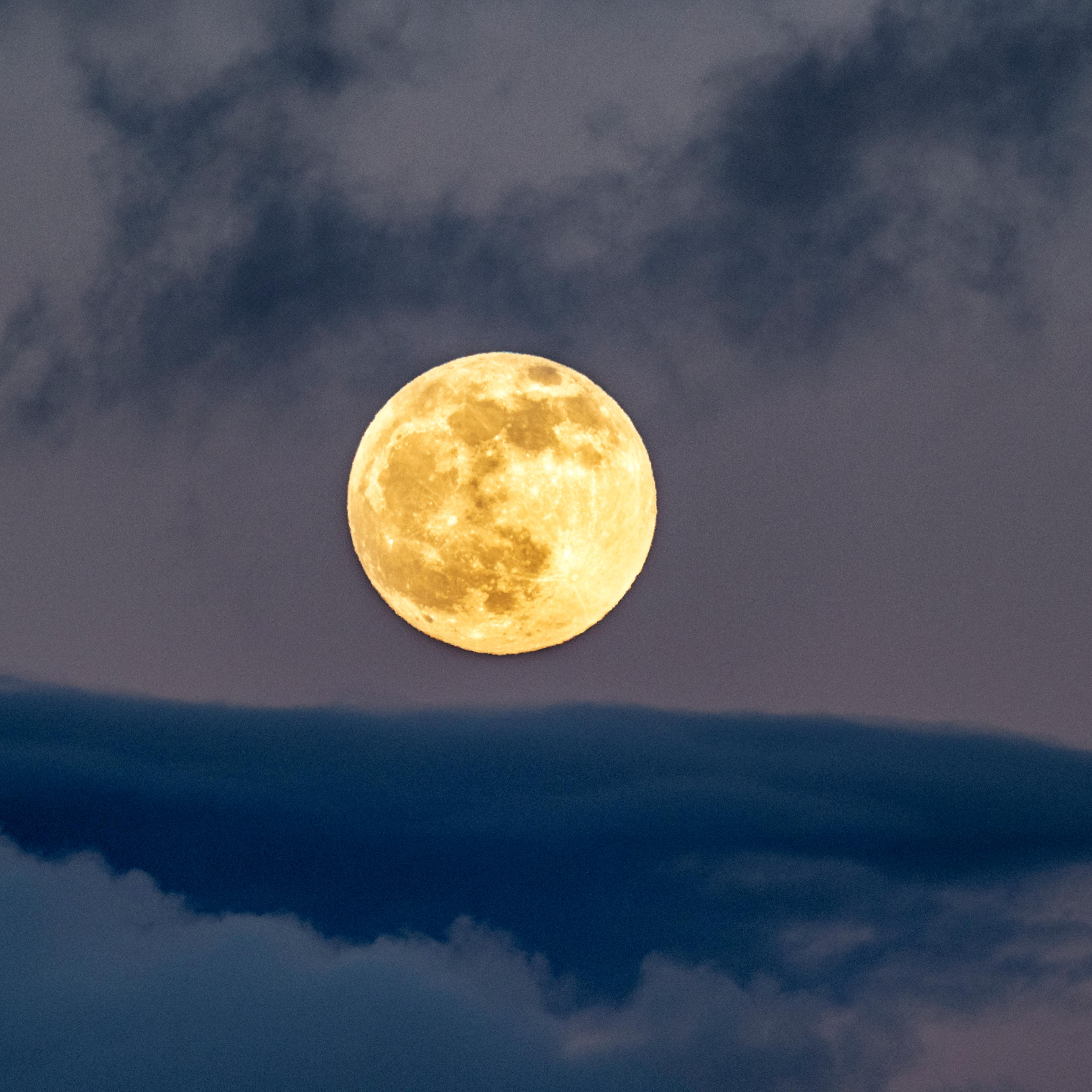 Full frame of the full moon at sunset with a sky with clouds.