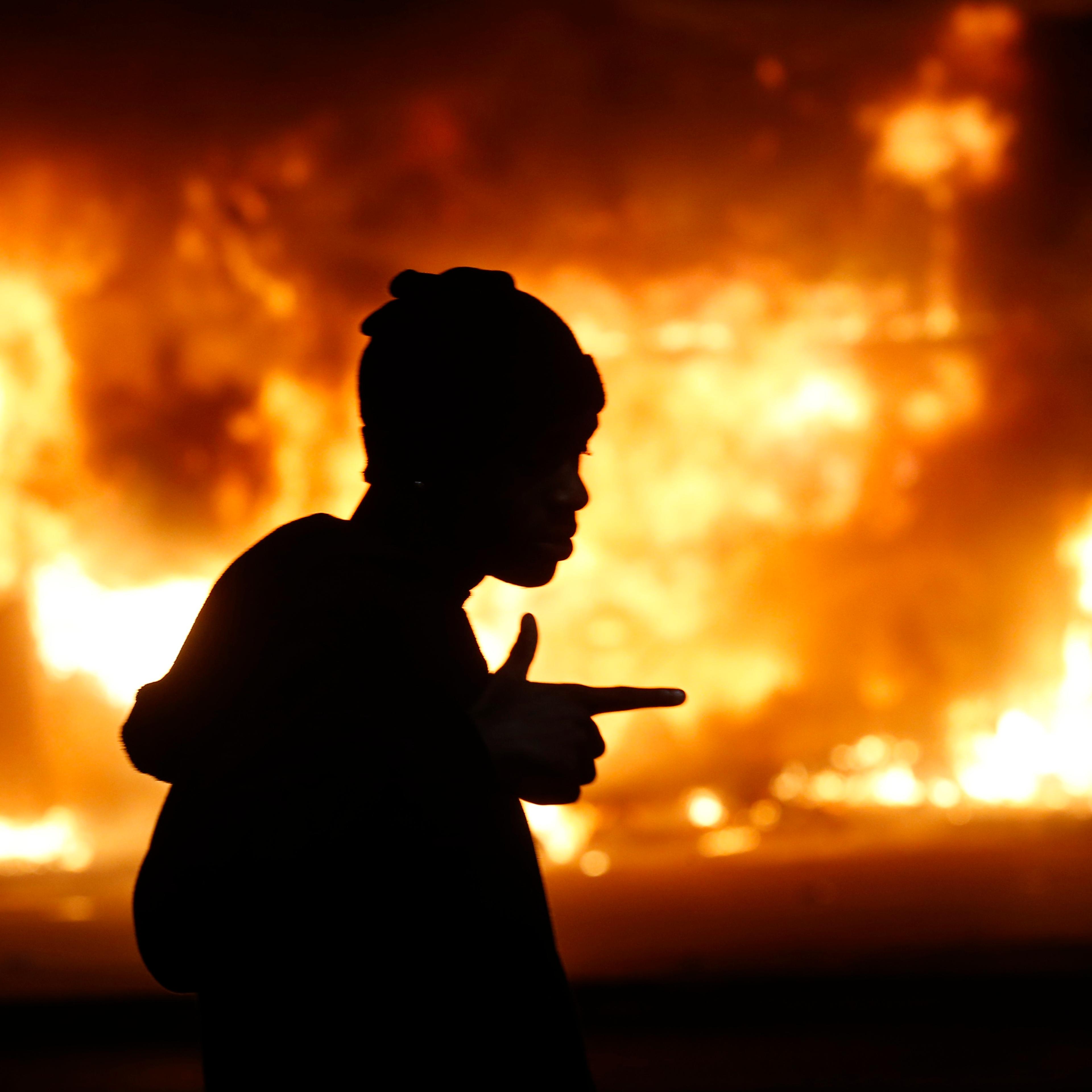 A man walks past a burning building during rioting after a grand jury returned no indictment in the shooting of Michael Brown in Ferguson, Missouri