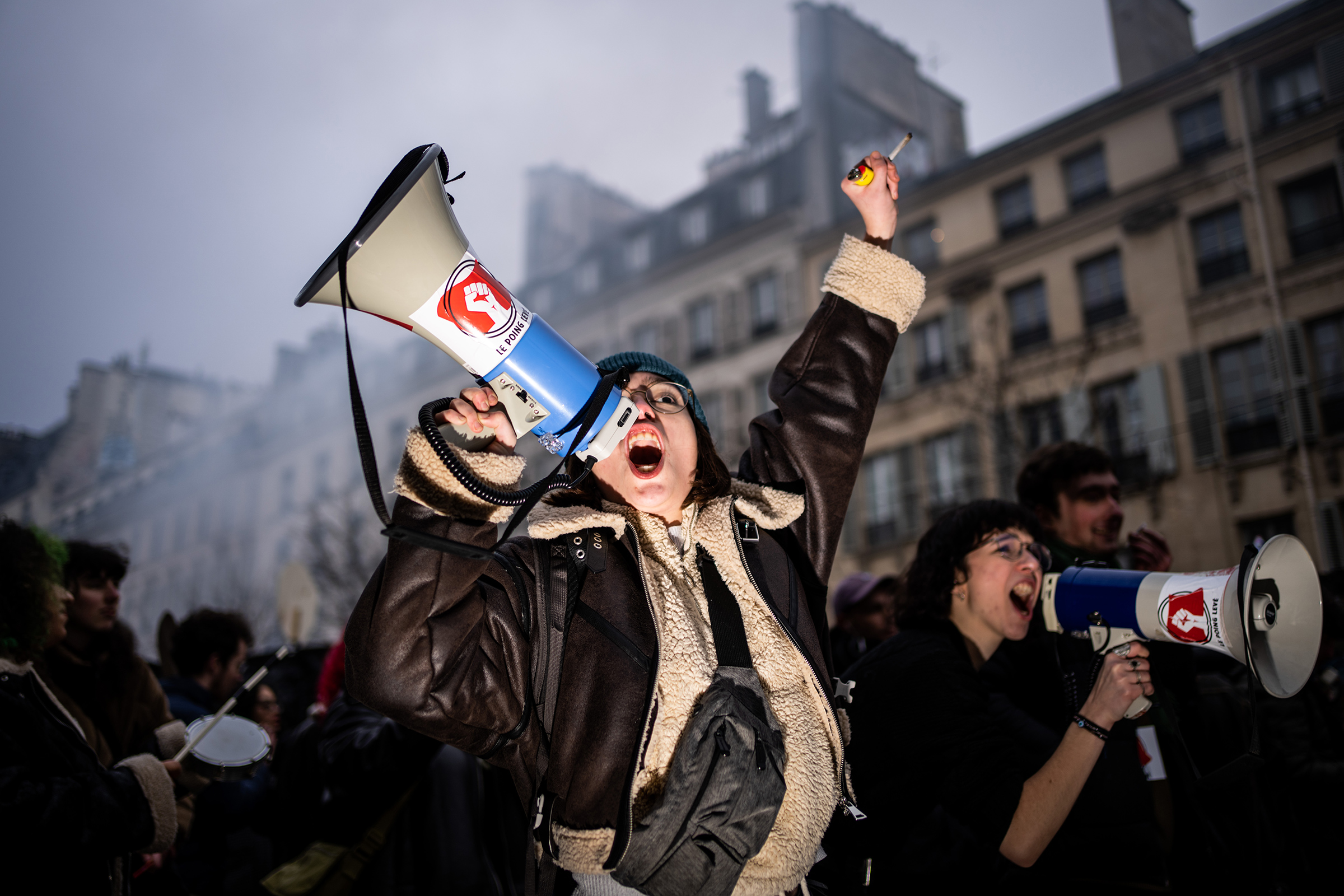 A young woman demonstrator from the student union shouts anti-reform slogans with a megaphone bearing the message 'Fist up' during the first day of mobilization against the French government's pension reform plan, in Paris, Jan. 19.