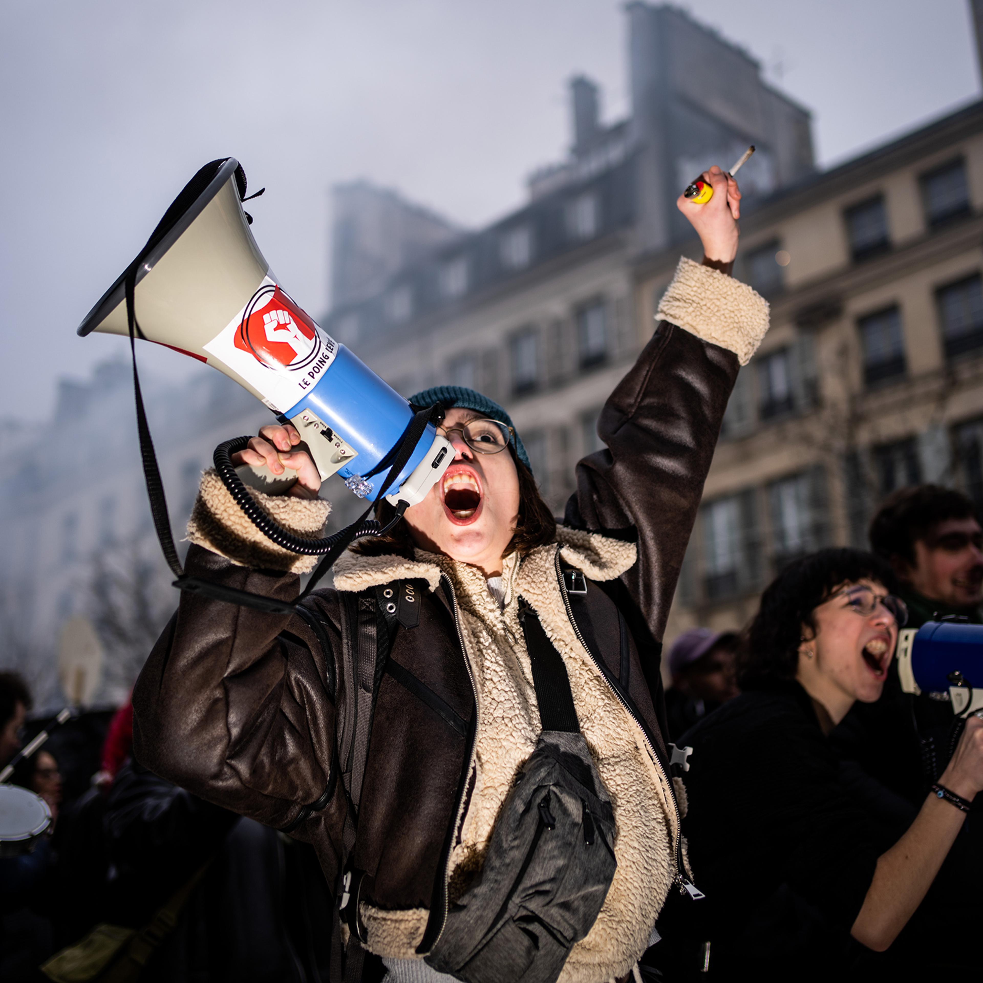 A young woman demonstrator from the student union shouts anti-reform slogans with a megaphone bearing the message 'Fist up' during the first day of mobilization against the French government's pension reform plan, in Paris, Jan. 19.
