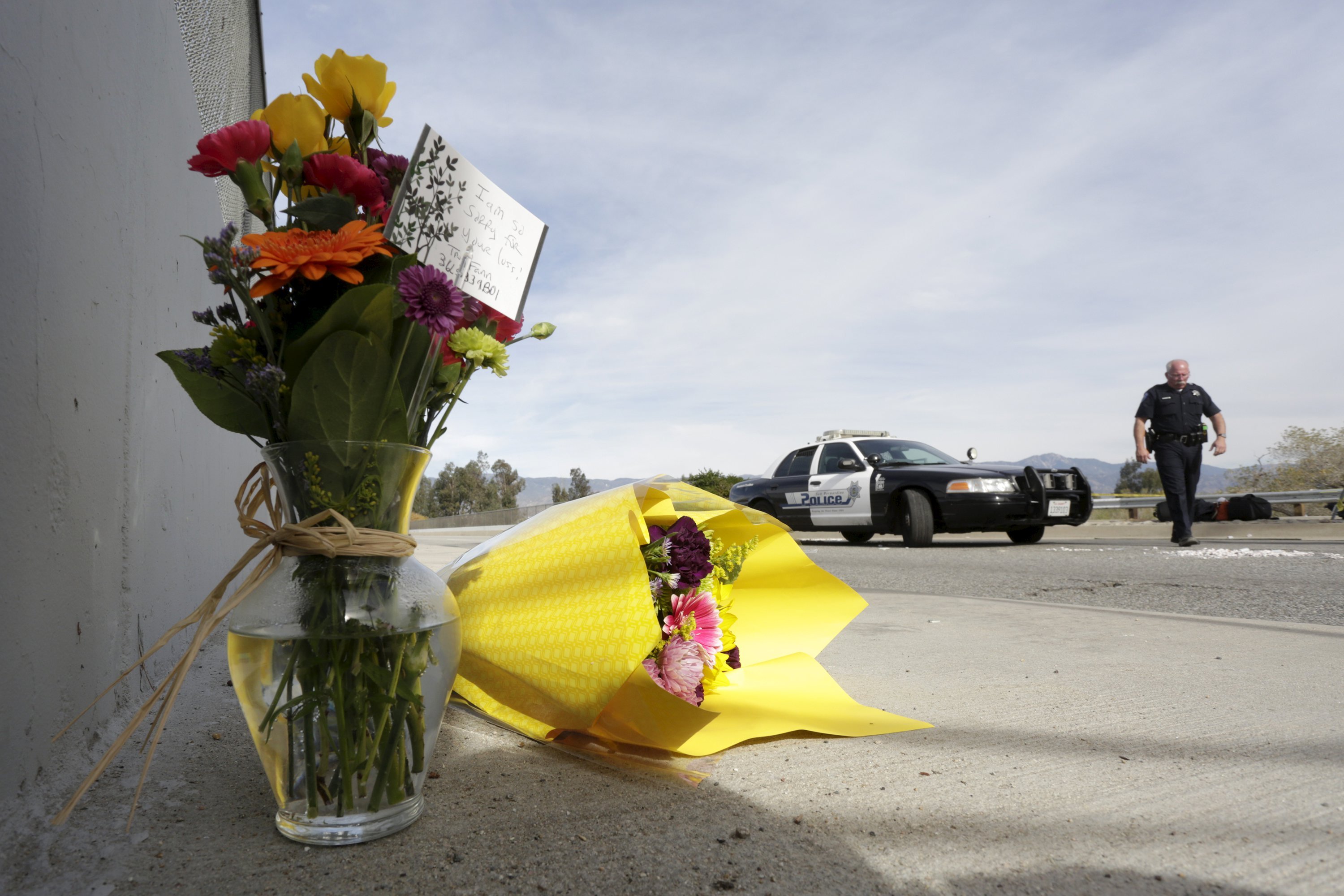 A San Bernardino police officer stands near flowers left near the scene of Wedneday's shooting rampage in San Bernardino