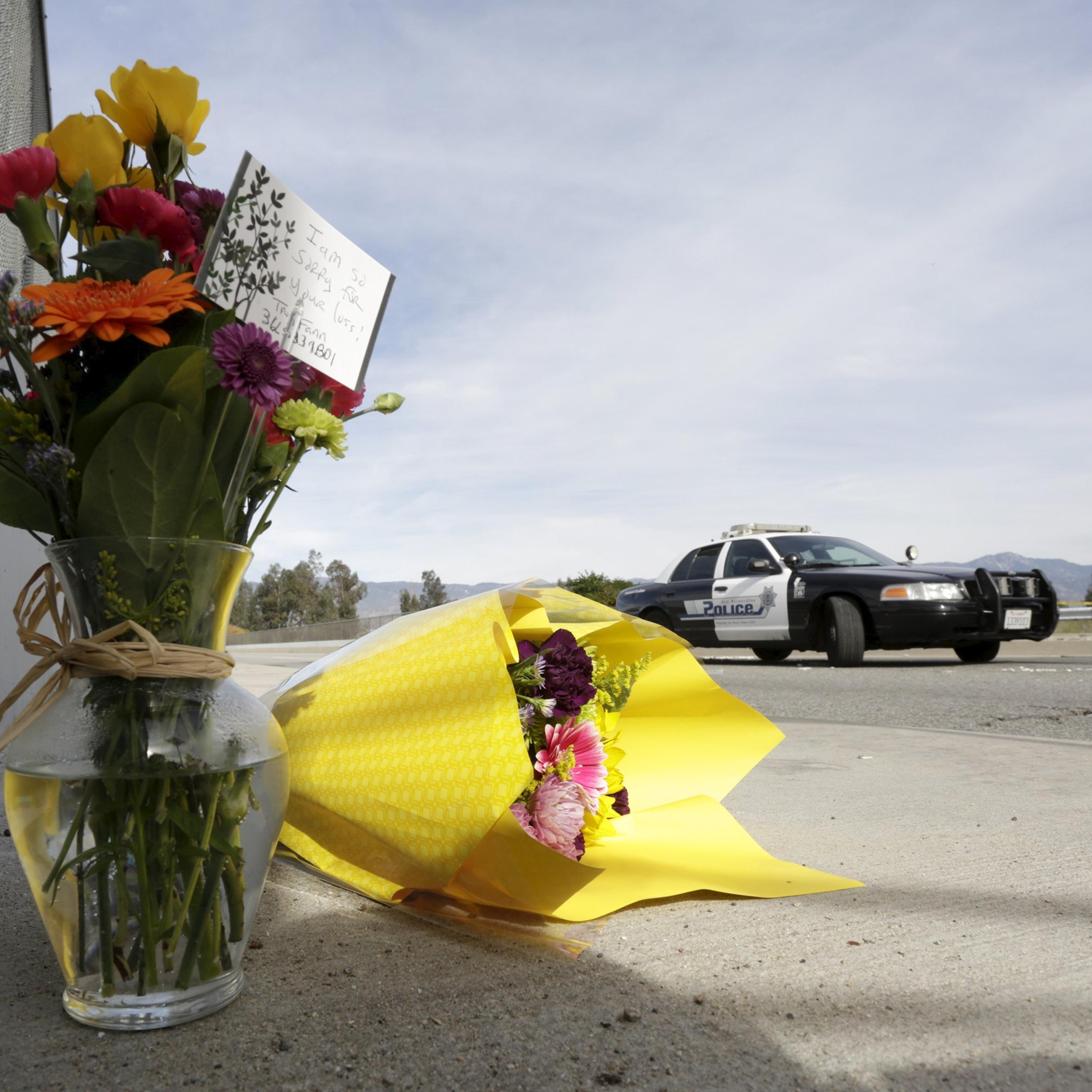 A San Bernardino police officer stands near flowers left near the scene of Wedneday's shooting rampage in San Bernardino