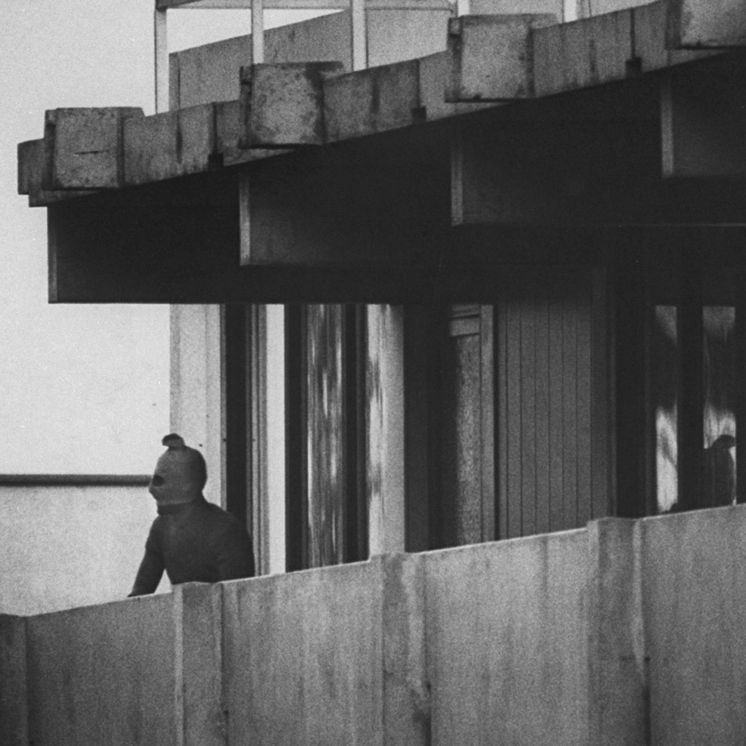 A Black September terrorist looks from the balcony of an apartment where Israeli Olympic team members are held hostage, Munich, September 1972.