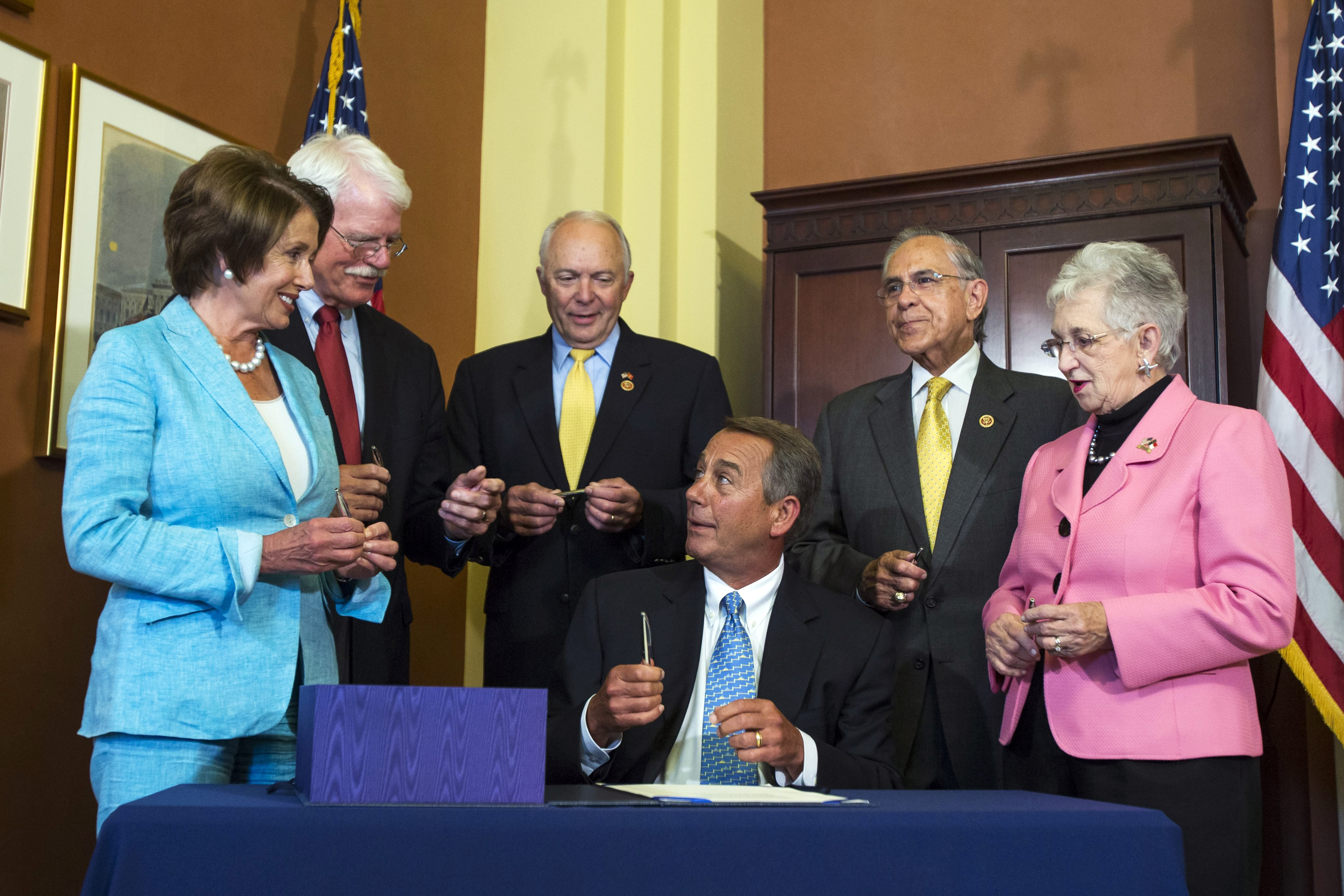 Republican Speaker of the House John Boehner (C) reacts after signing the Workforce Innovation and Opportunity Act with (from left to right) Democratic House Minority Leader Nancy Pelosi, Democratic Congressman George Miller, Republican Congressman John 