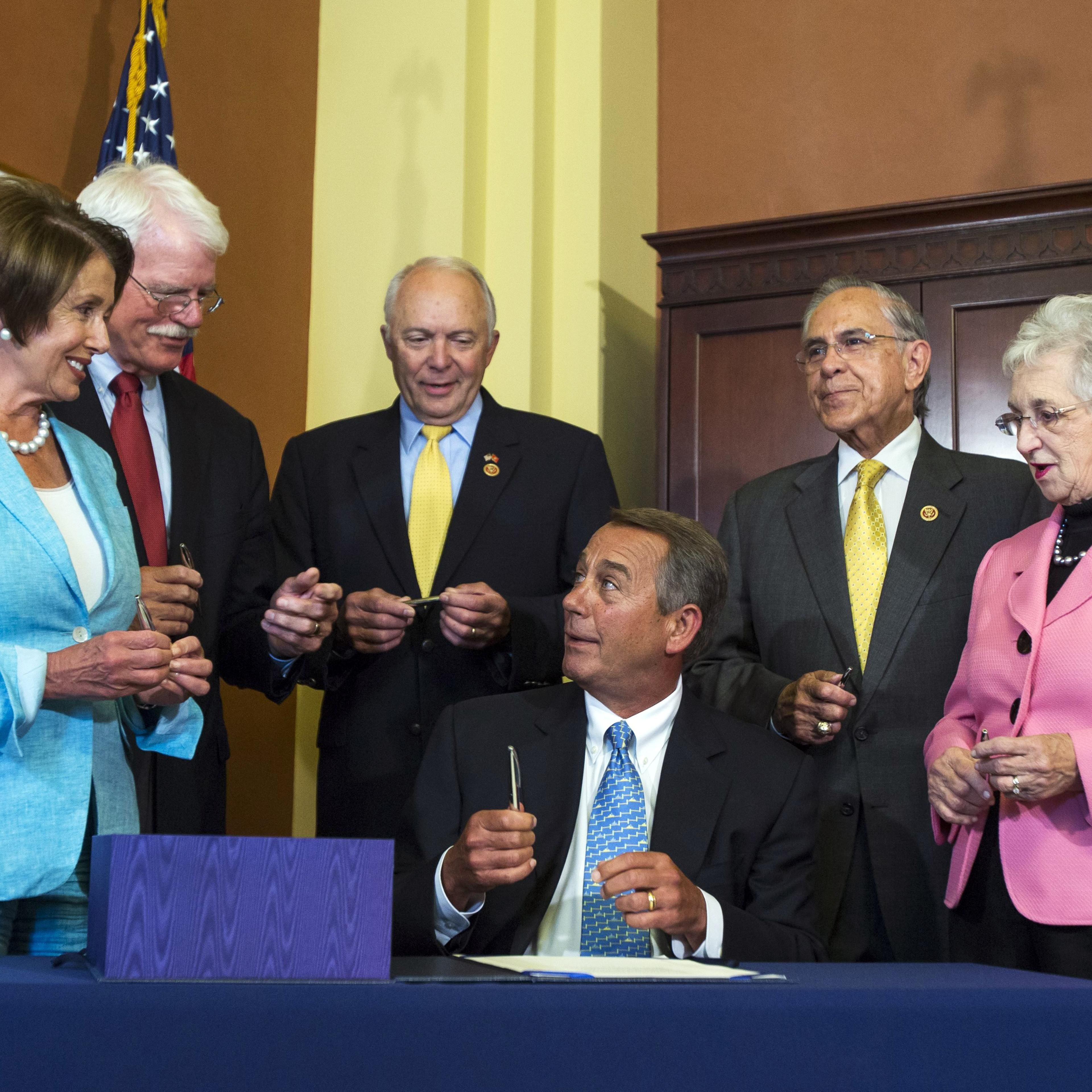 Republican Speaker of the House John Boehner (C) reacts after signing the Workforce Innovation and Opportunity Act with (from left to right) Democratic House Minority Leader Nancy Pelosi, Democratic Congressman George Miller, Republican Congressman John