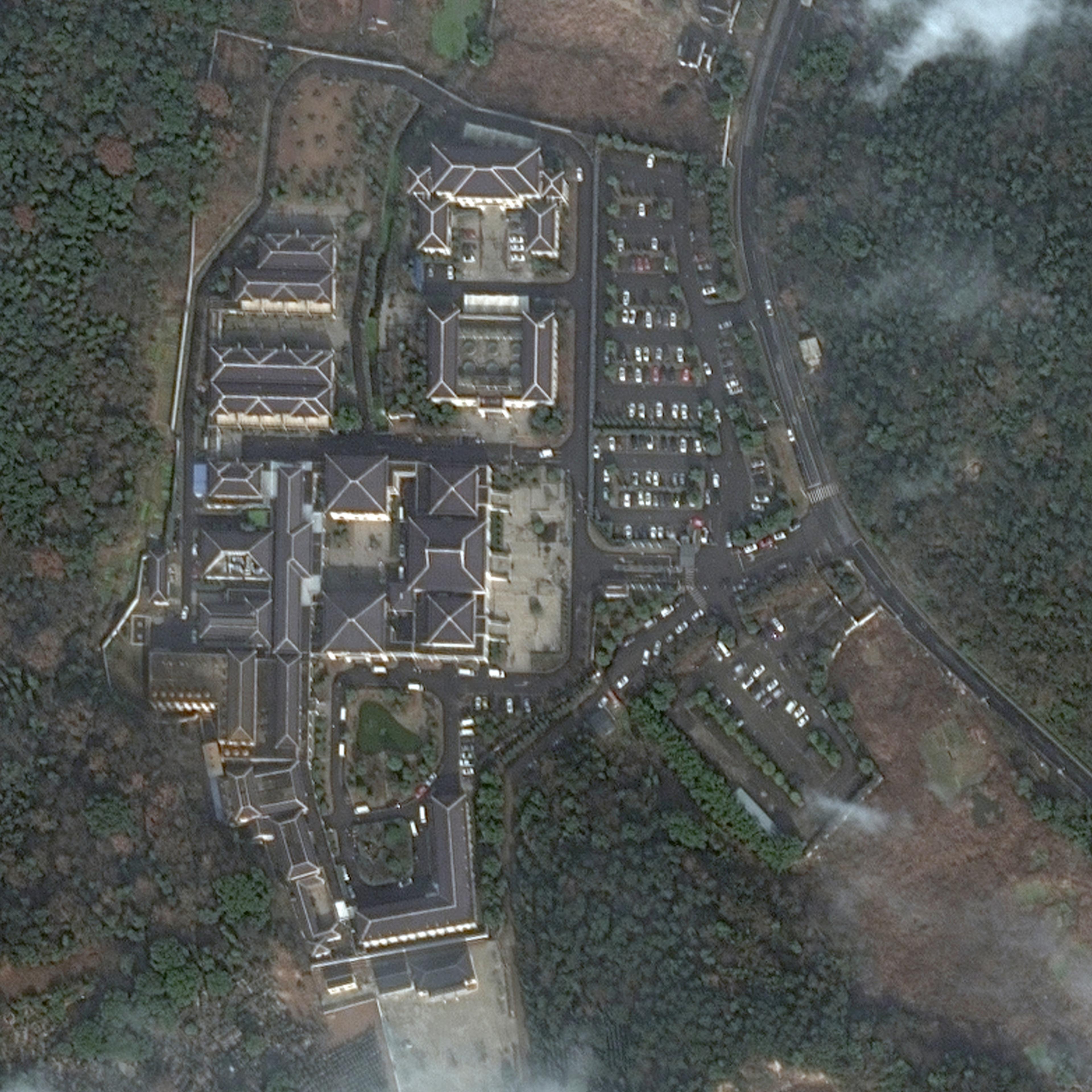 A satellite image taken on Jan. 3, 2022, shows a funeral home in Huzhou with a packed parking lot. An image taken in January of last year features far fewer cars.