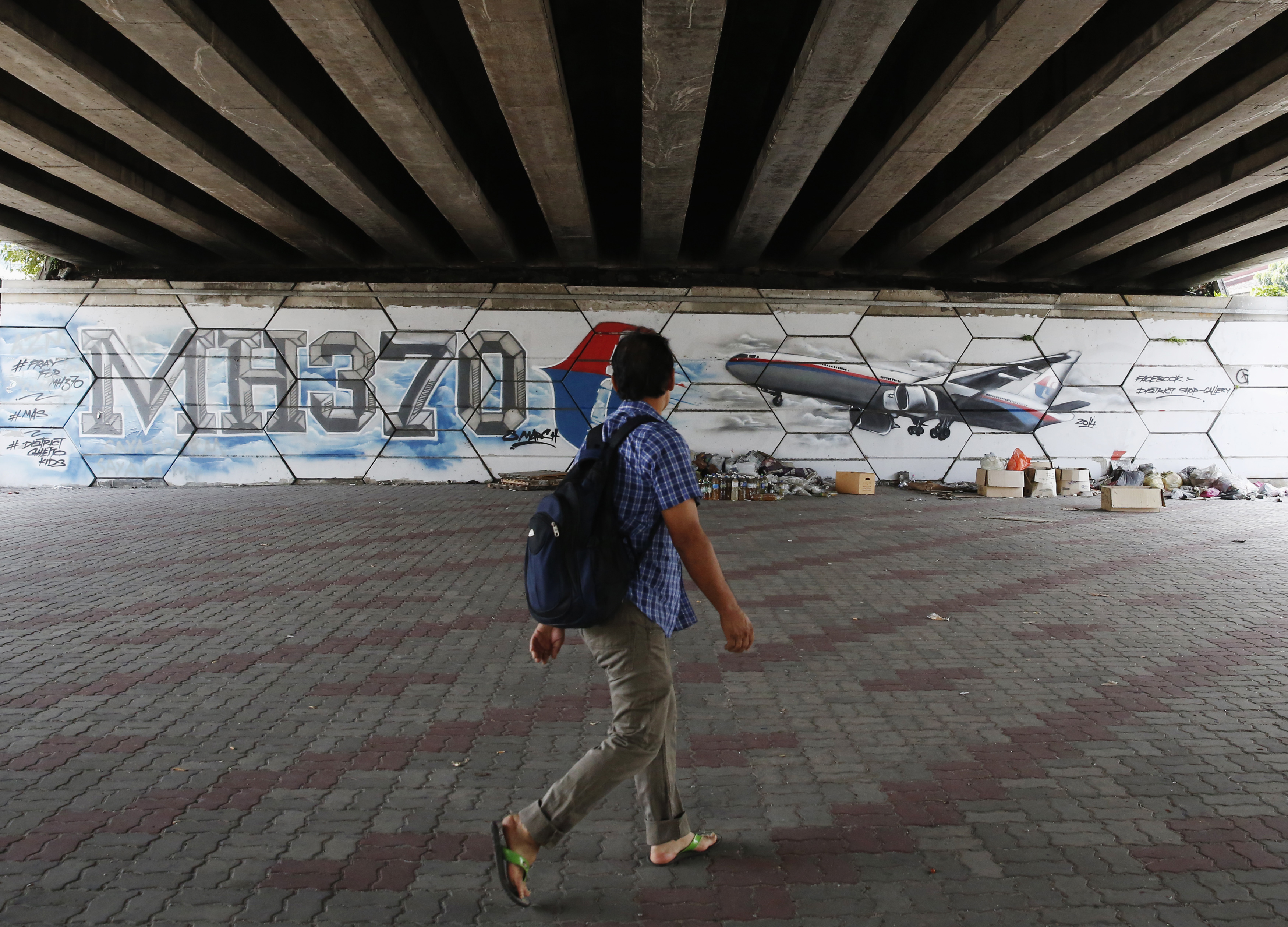 A man walks past graffiti depicting flight MH370 on the one year anniversary of its disappearance in Kuala Lumpur