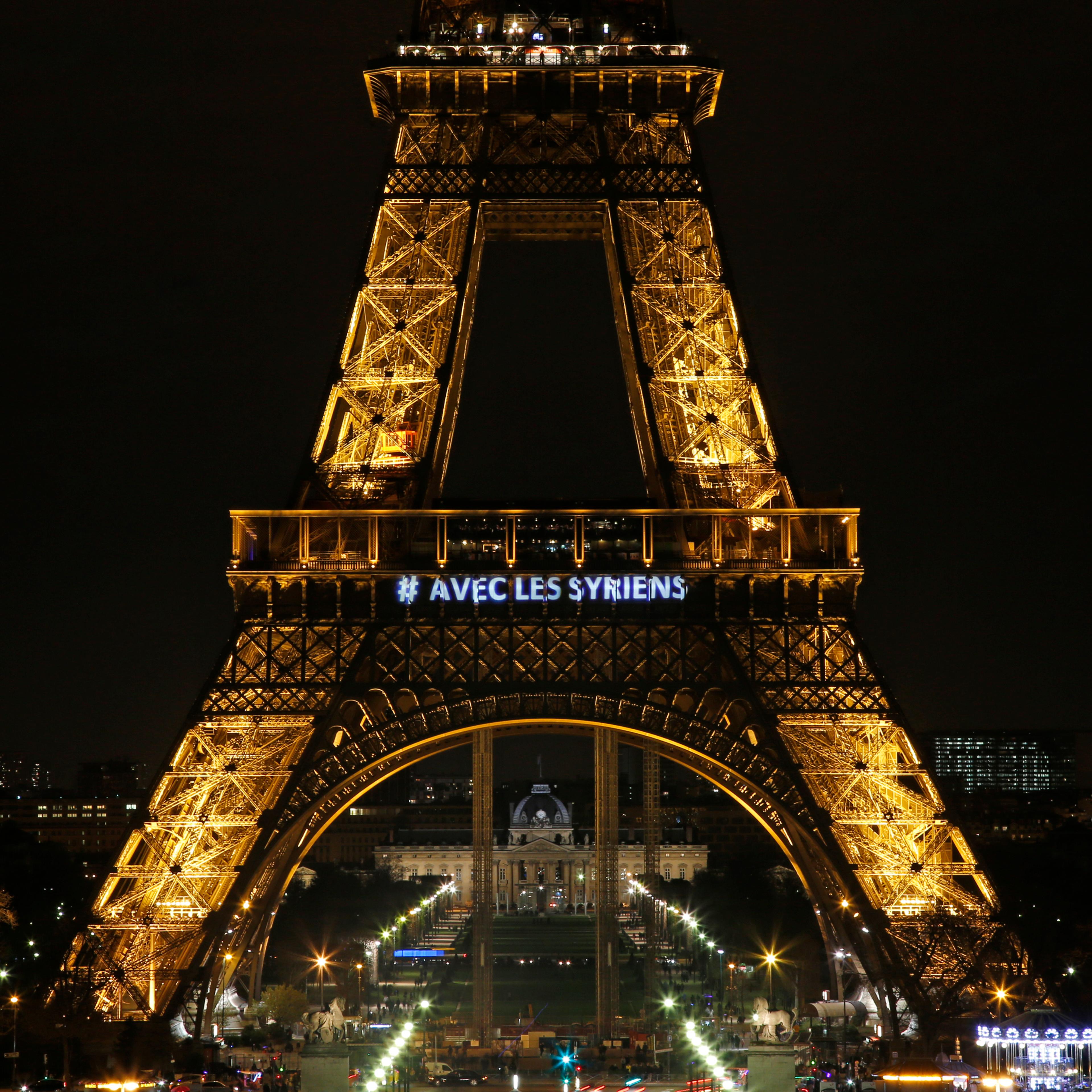 The words "With the Syrians" are displayed on the Eiffel Tower in support of Syrians on the third anniversary of the conflict, in Paris