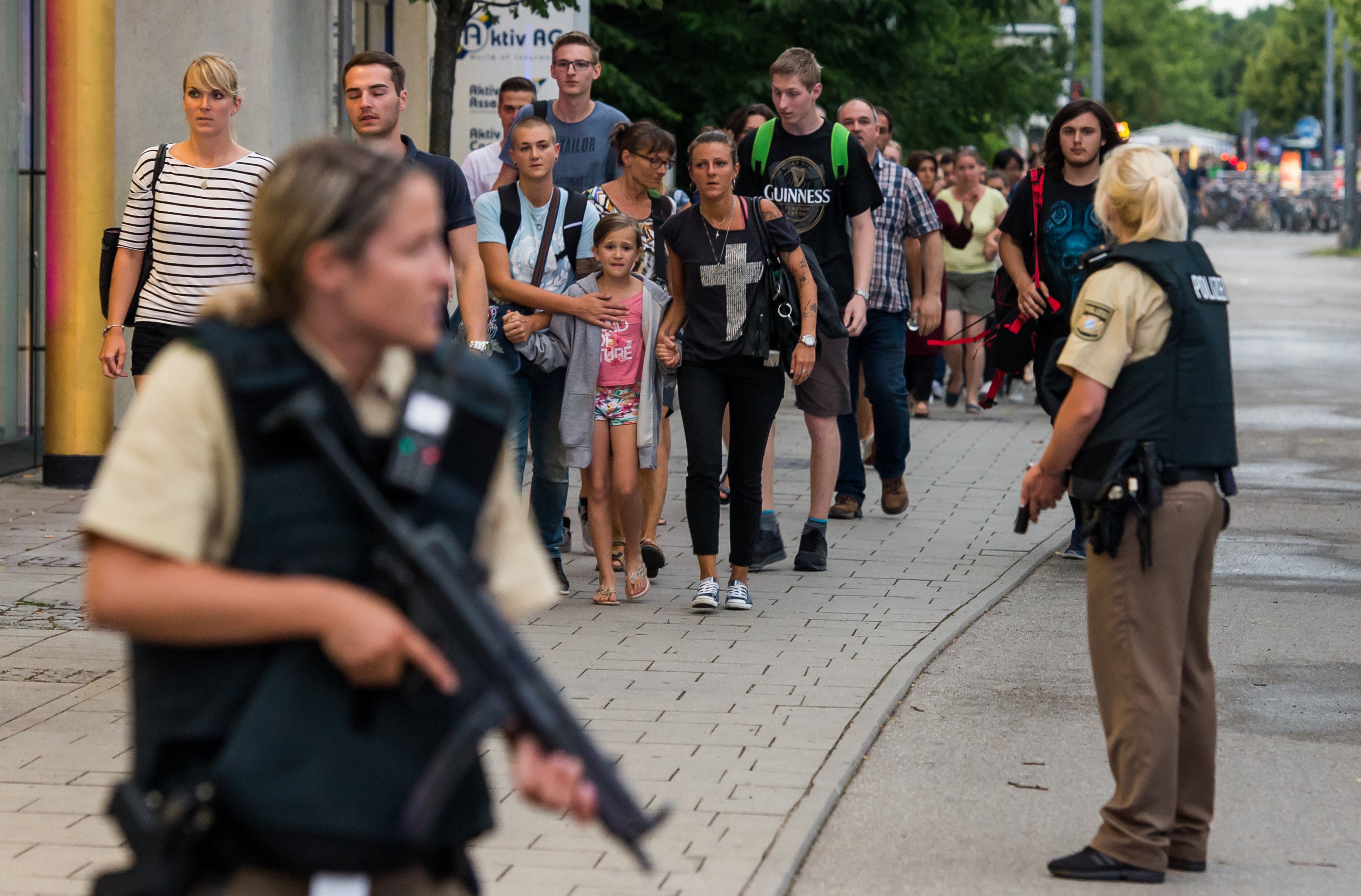 Police officers escort people from inside the shopping center as they respond to a shooting at the Olympia Einkaufzentrum (OEZ) at July 22, 2016 in Munich.