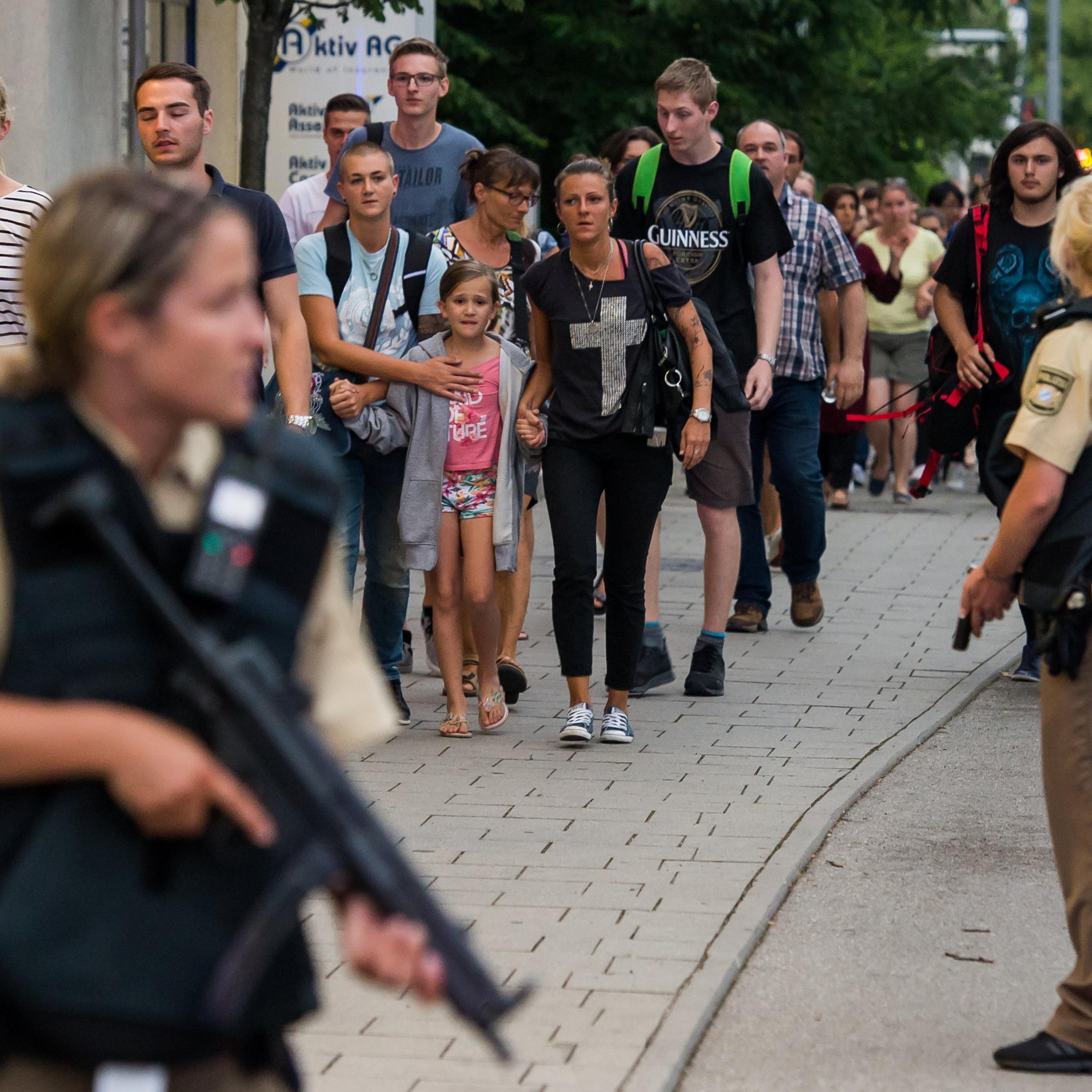 Police officers escort people from inside the shopping center as they respond to a shooting at the Olympia Einkaufzentrum (OEZ) at July 22, 2016 in Munich.