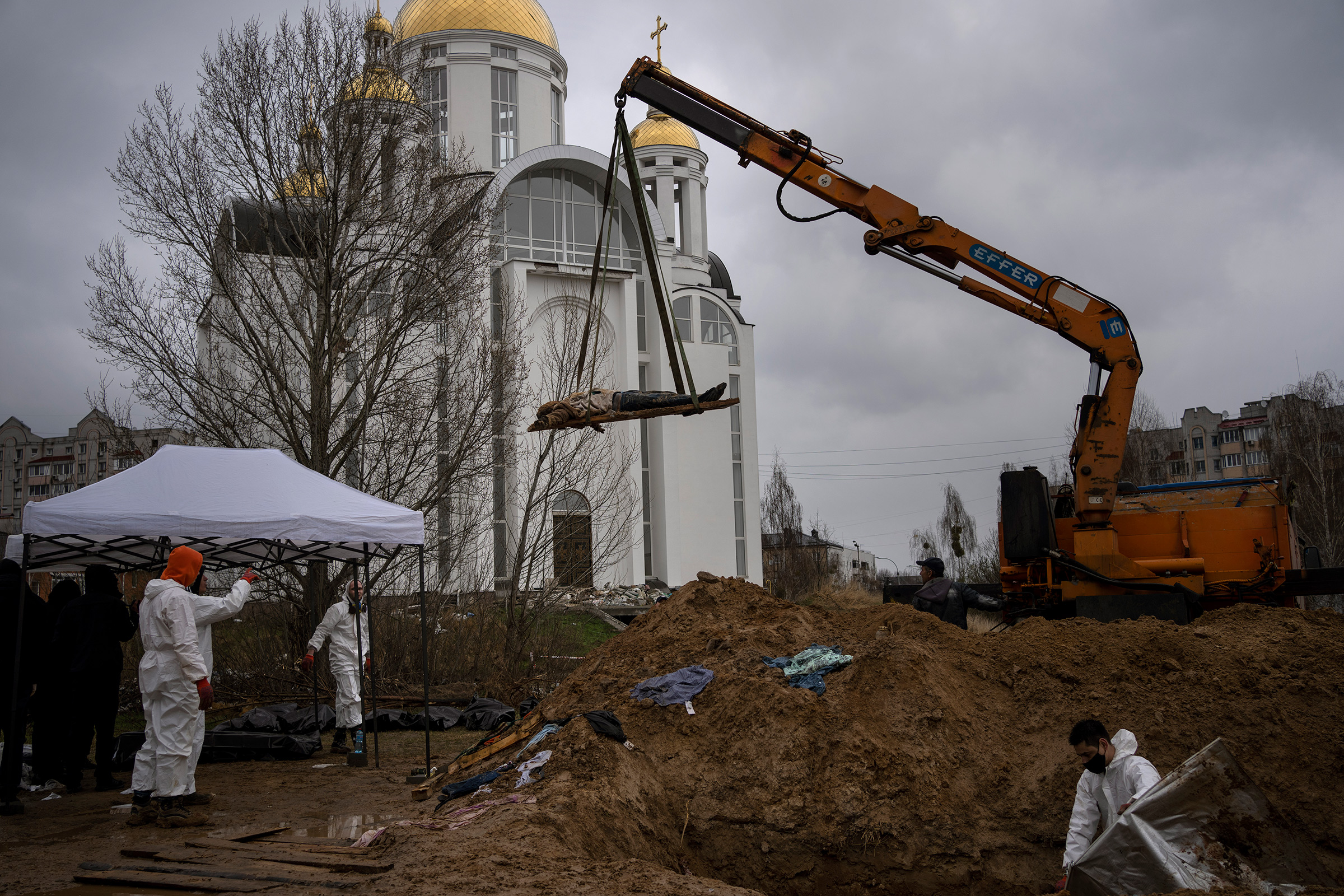 A crane lifts a corpse from a mass grave in Bucha; authorities say more than 400 civilians were murdered 