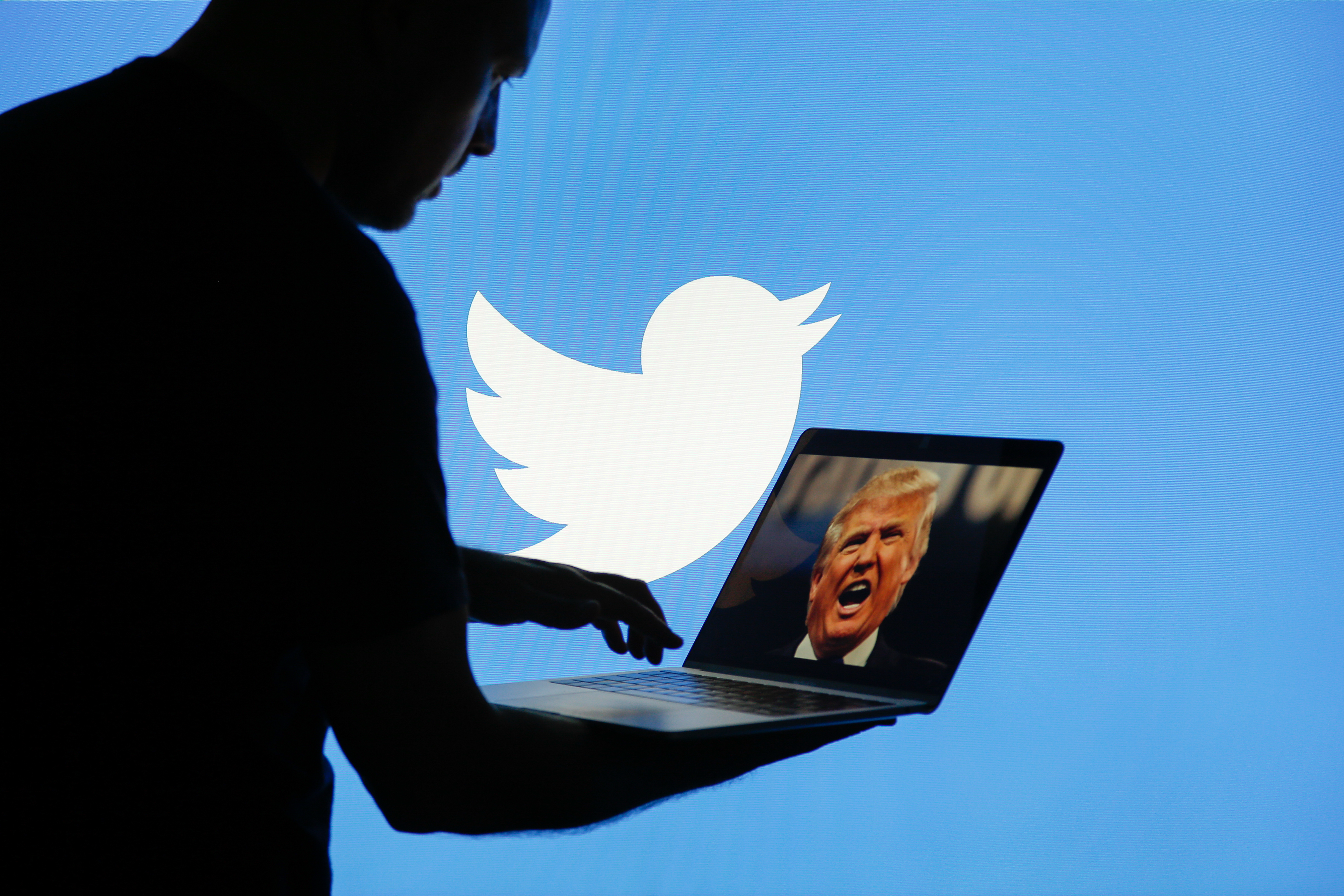 A man is seen with a laptop depicting an image of US president Donald Trump with a Twitter logo displayed in the background in this photo illustration on July 2, 2017
