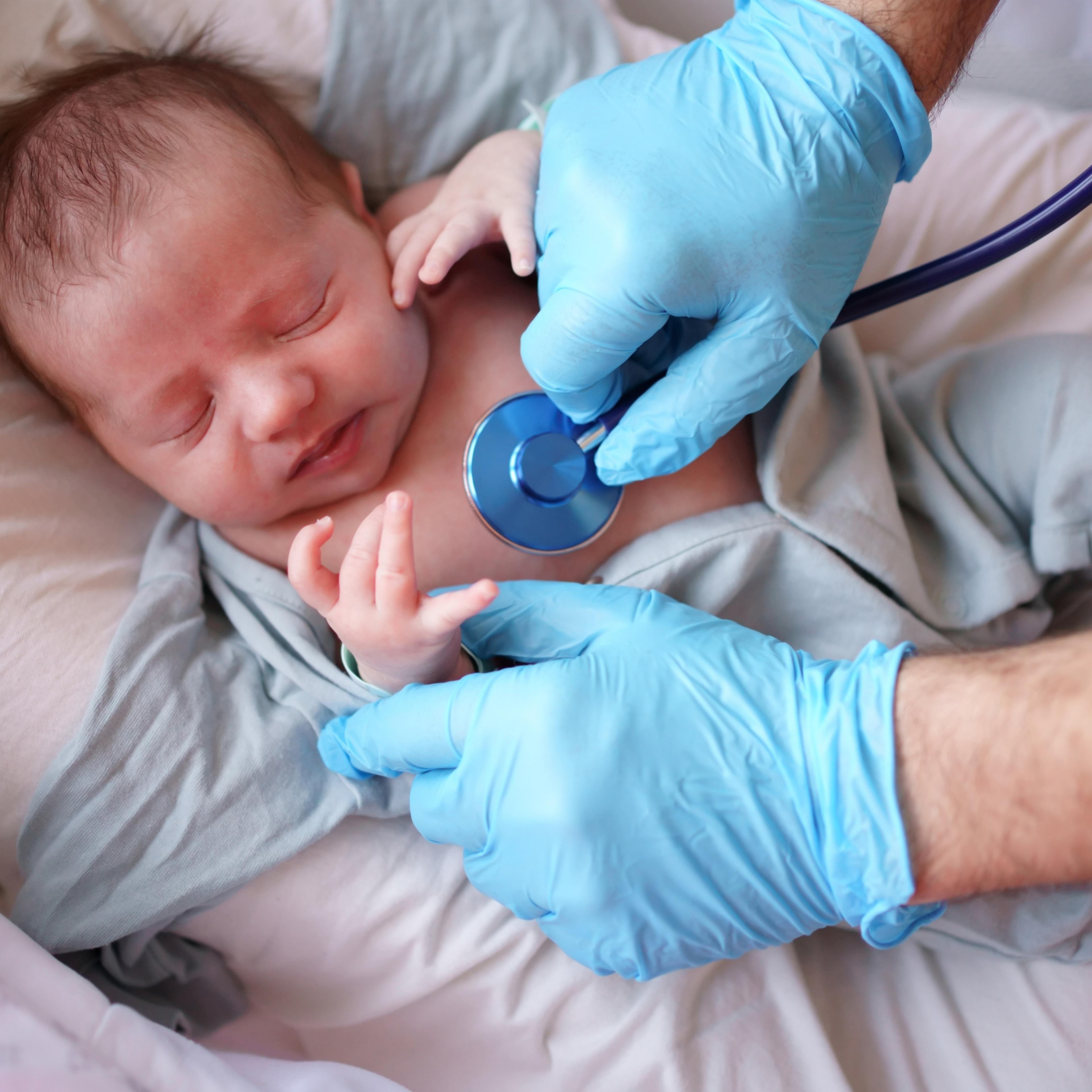 Doctor uses stethoscope to listen to baby