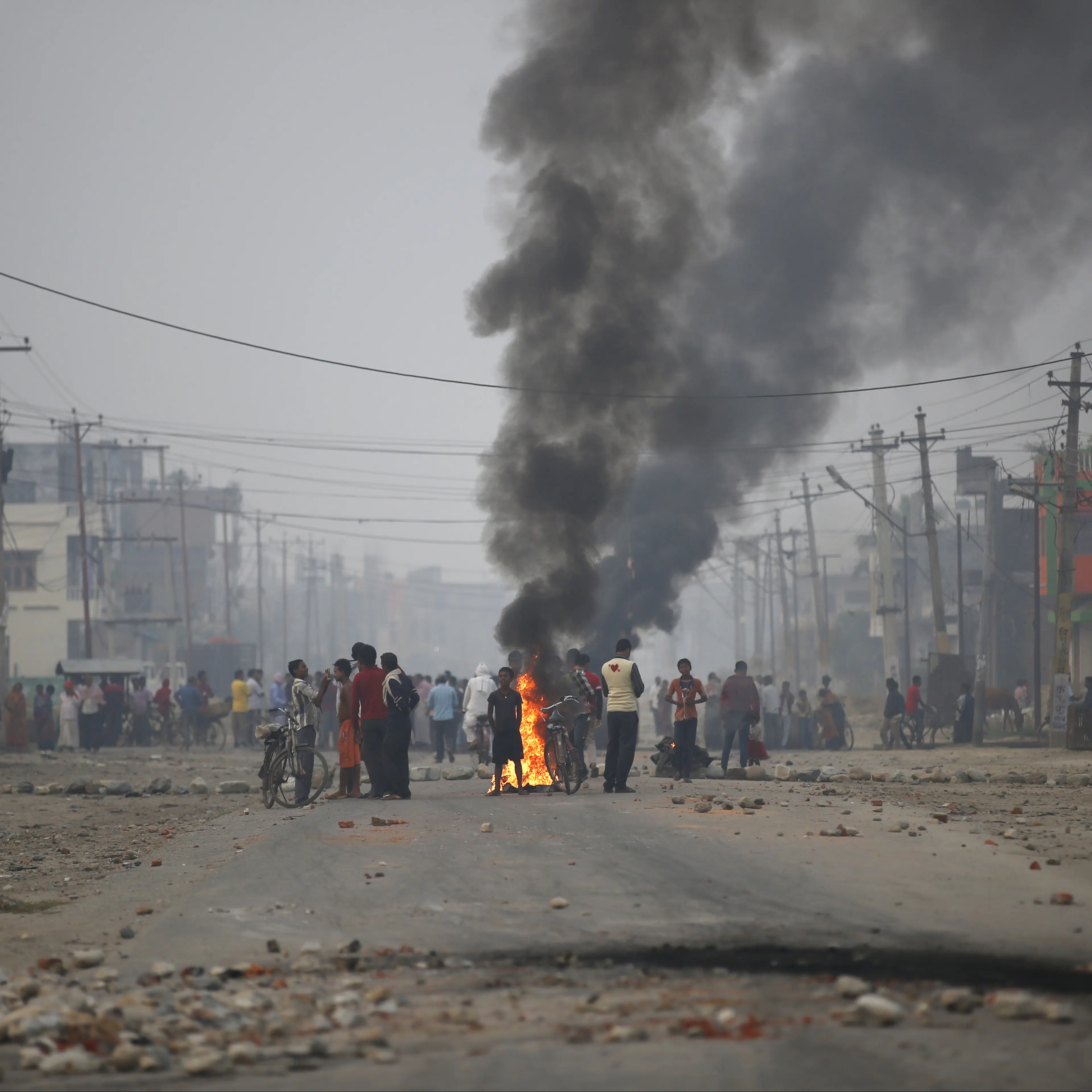 Protesters stand near burning tyres as they gather to block highway connecting Nepal and India, during general strike called by Madhesi protesters demonstrating against new constitution in Birgunj
