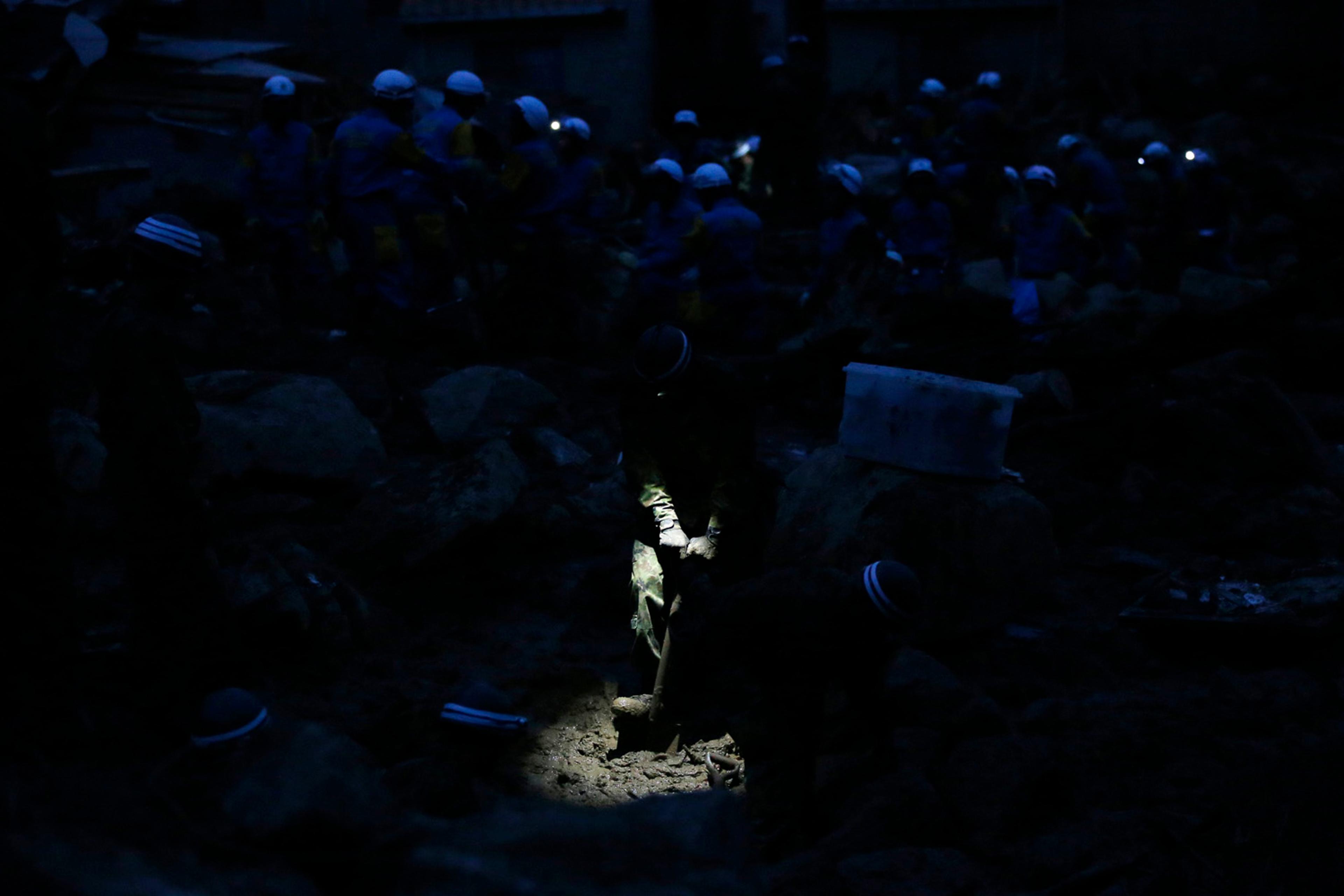 JSDF soldier searches for survivors at dusk at a site where a landslide swept through a residential area at Asaminami ward in Hiroshima