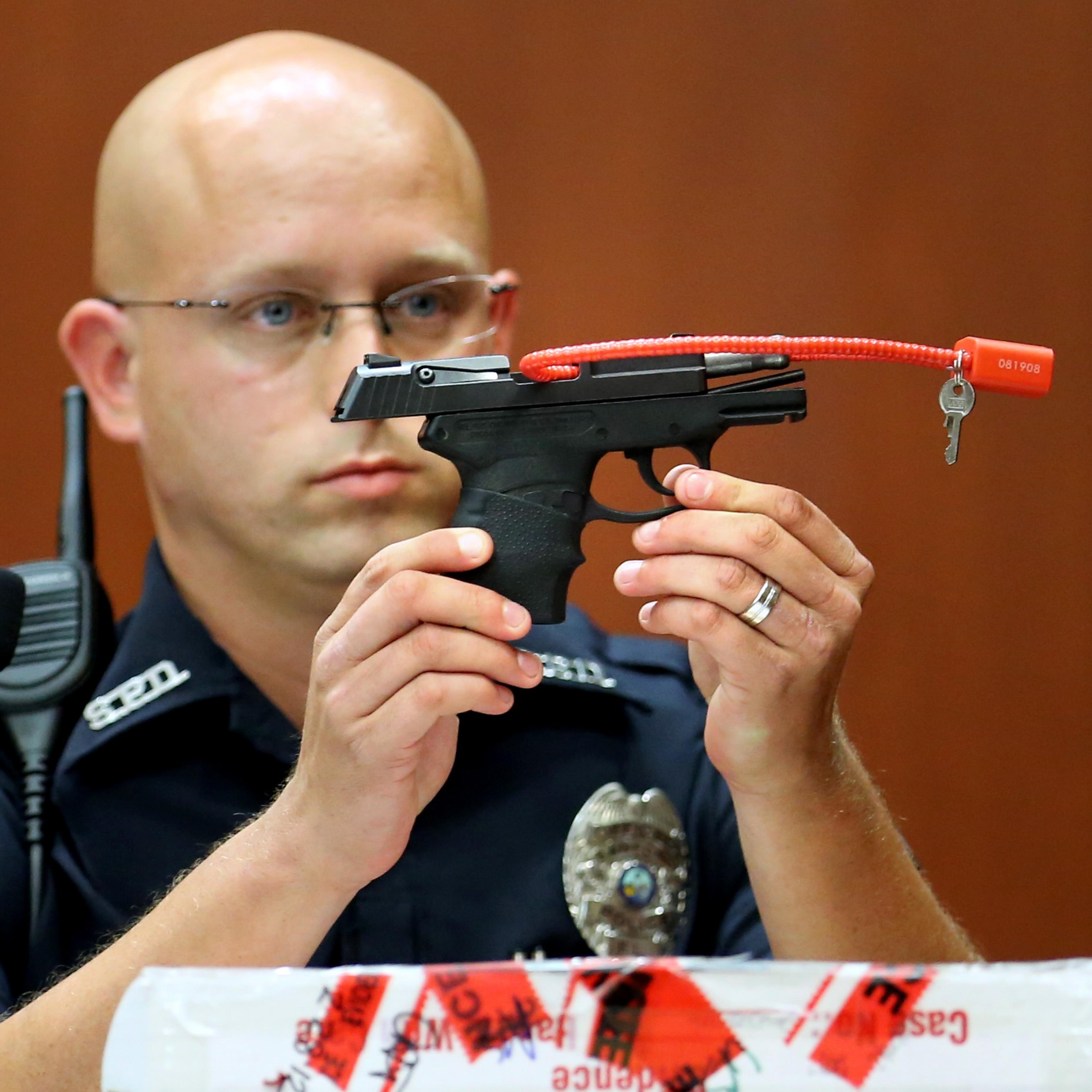 Sanford police officer Timothy Smith holds up the gun that was used to kill Trayvon Martin, while testifying on the 15th day of George Zimmerman's trial in Seminole Circuit Court in Sanford, Fla., June 28, 2013.