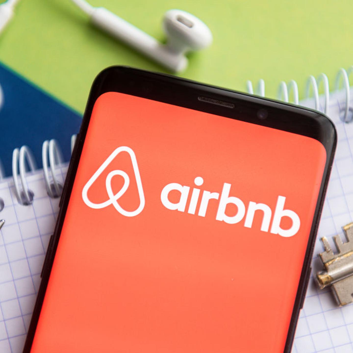 In this photo illustration, an Airbnb logo seen displayed on