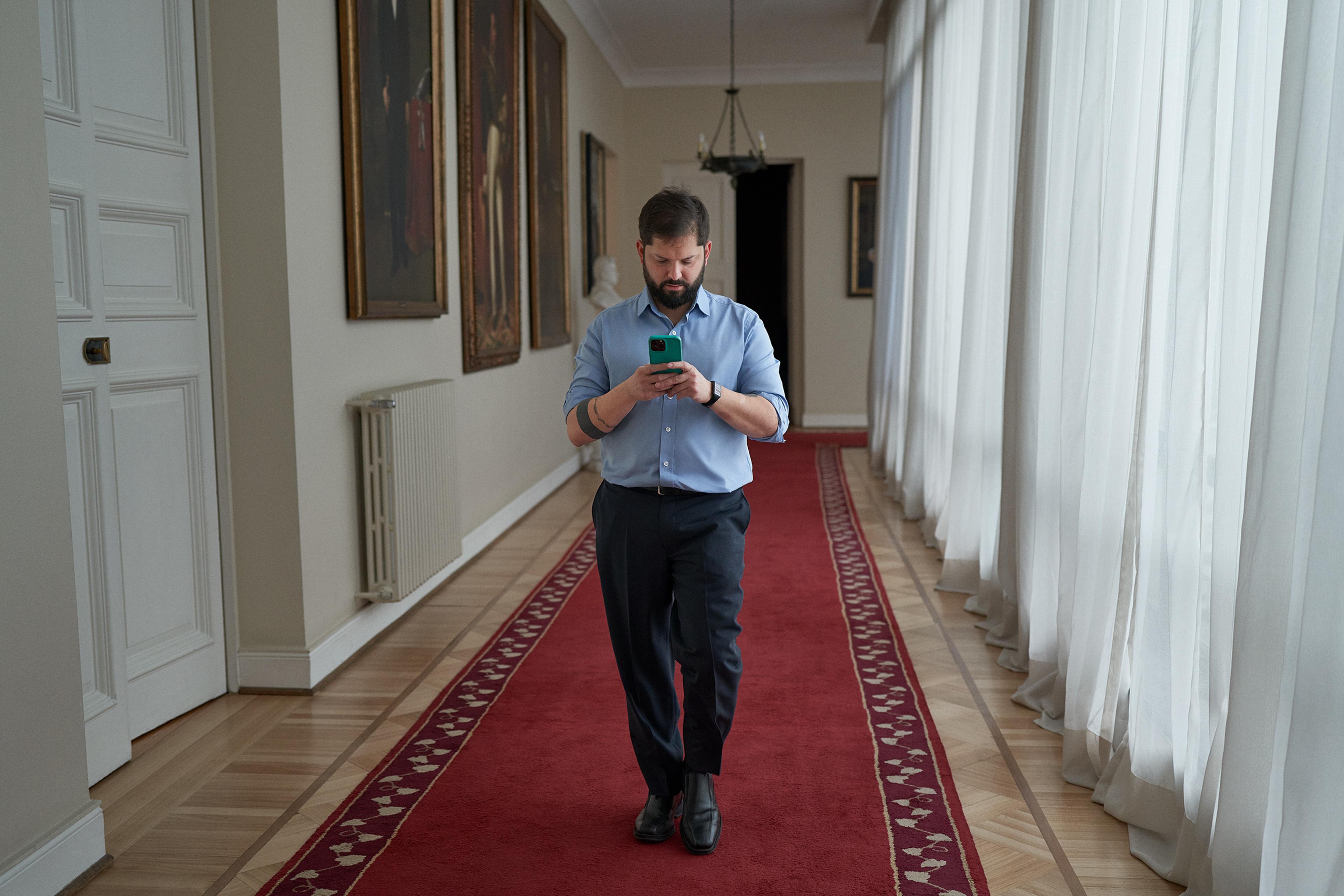 Boric checks his phone in the corridor of La Moneda presidential palace on Aug. 12