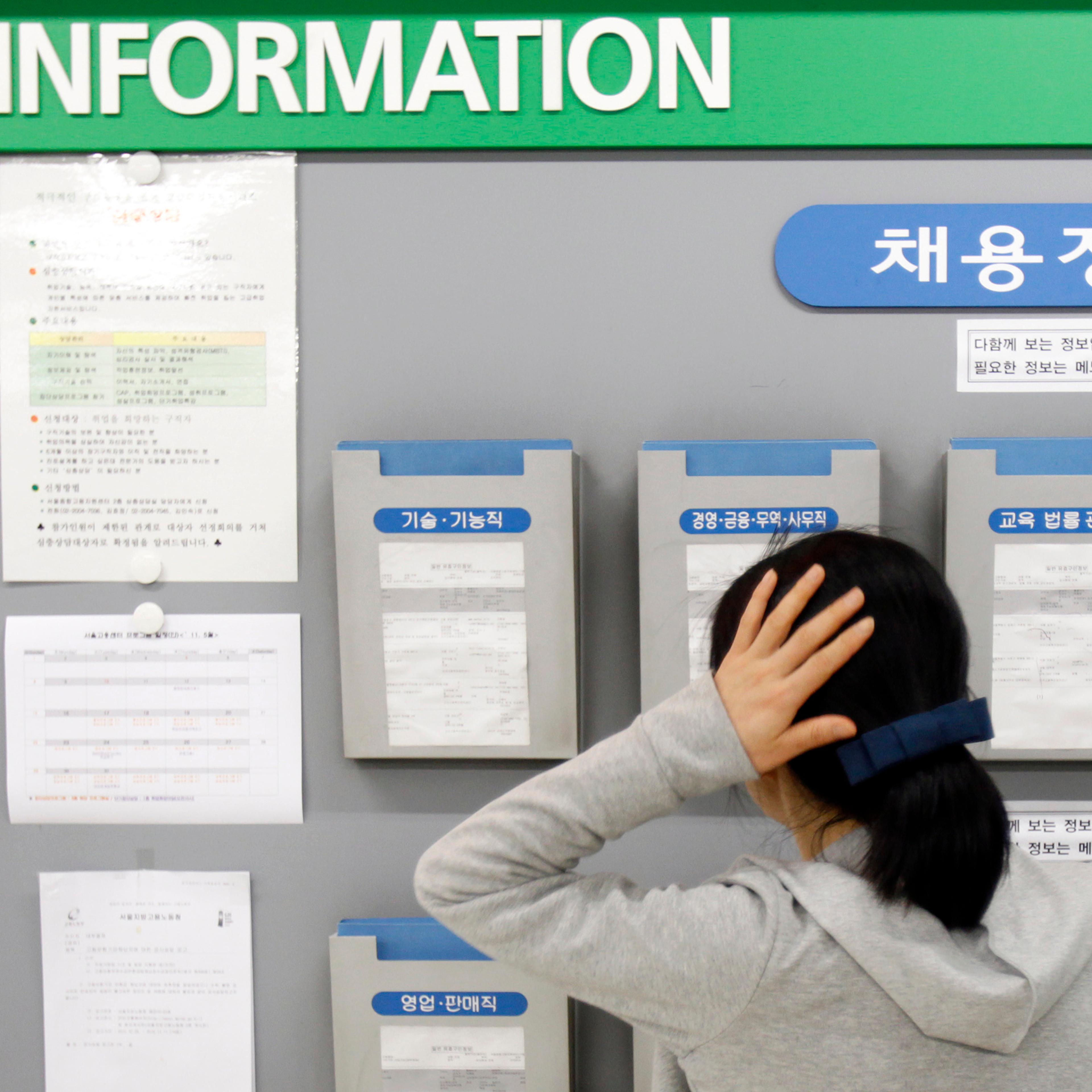 A jobseeker looks at a board showing job information at an office of the Employment Information Service in Seoul