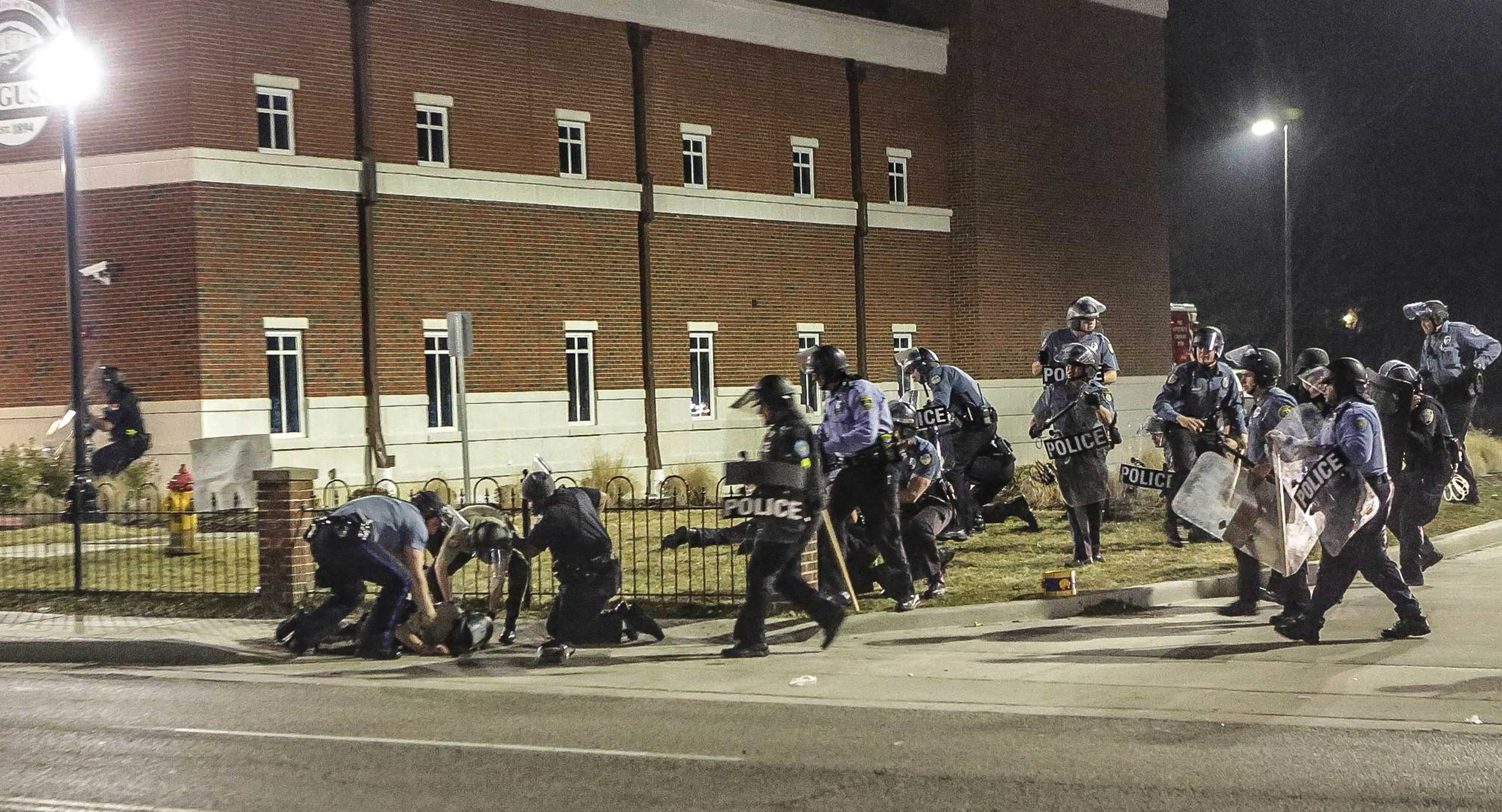 Police officers respond to a fellow officer hit by gunfire outside the Ferguson Police Headquarters in Ferguson