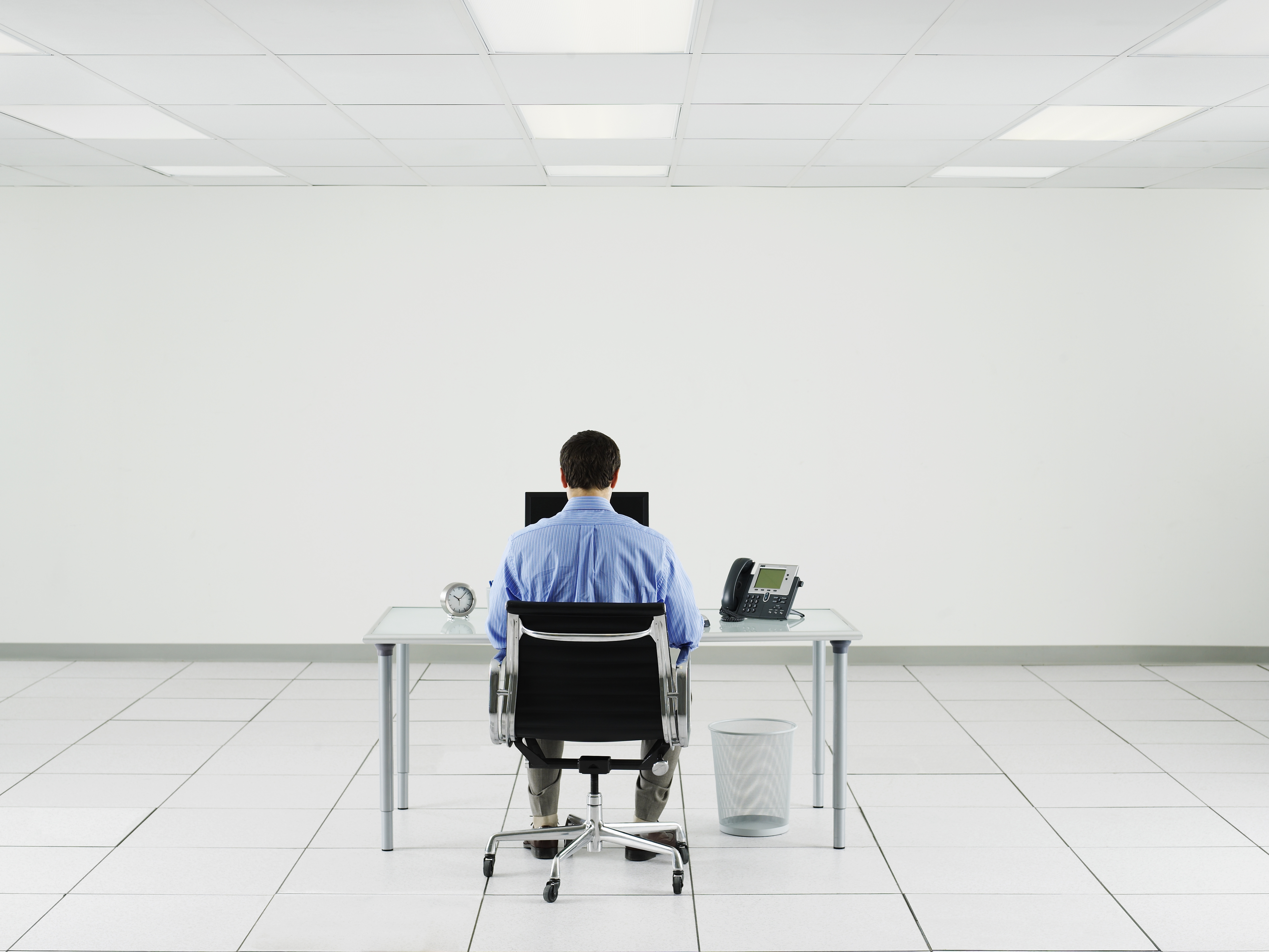 Man working at desk in empty room.